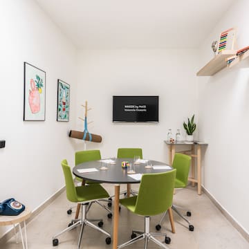 a room with a round table and green chairs