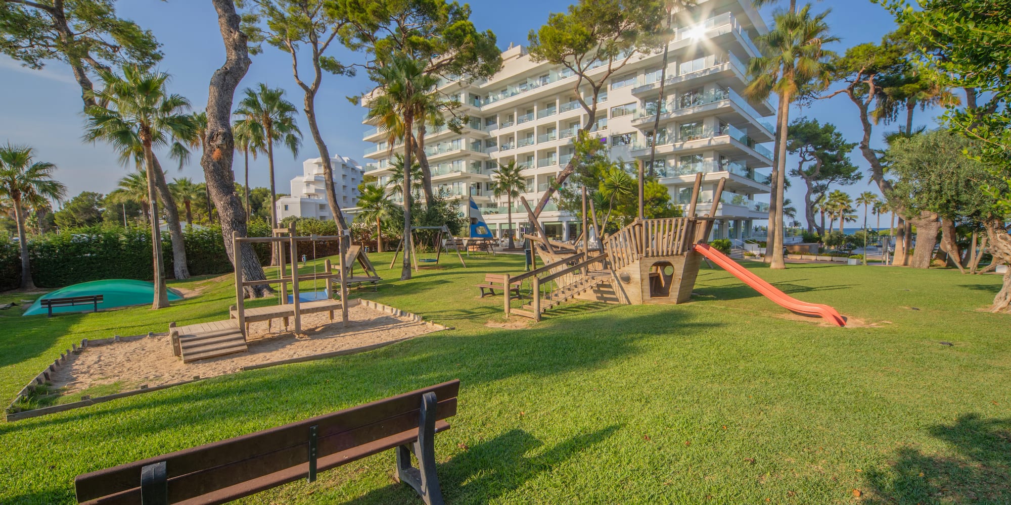 a playground in a park with trees and buildings in the background