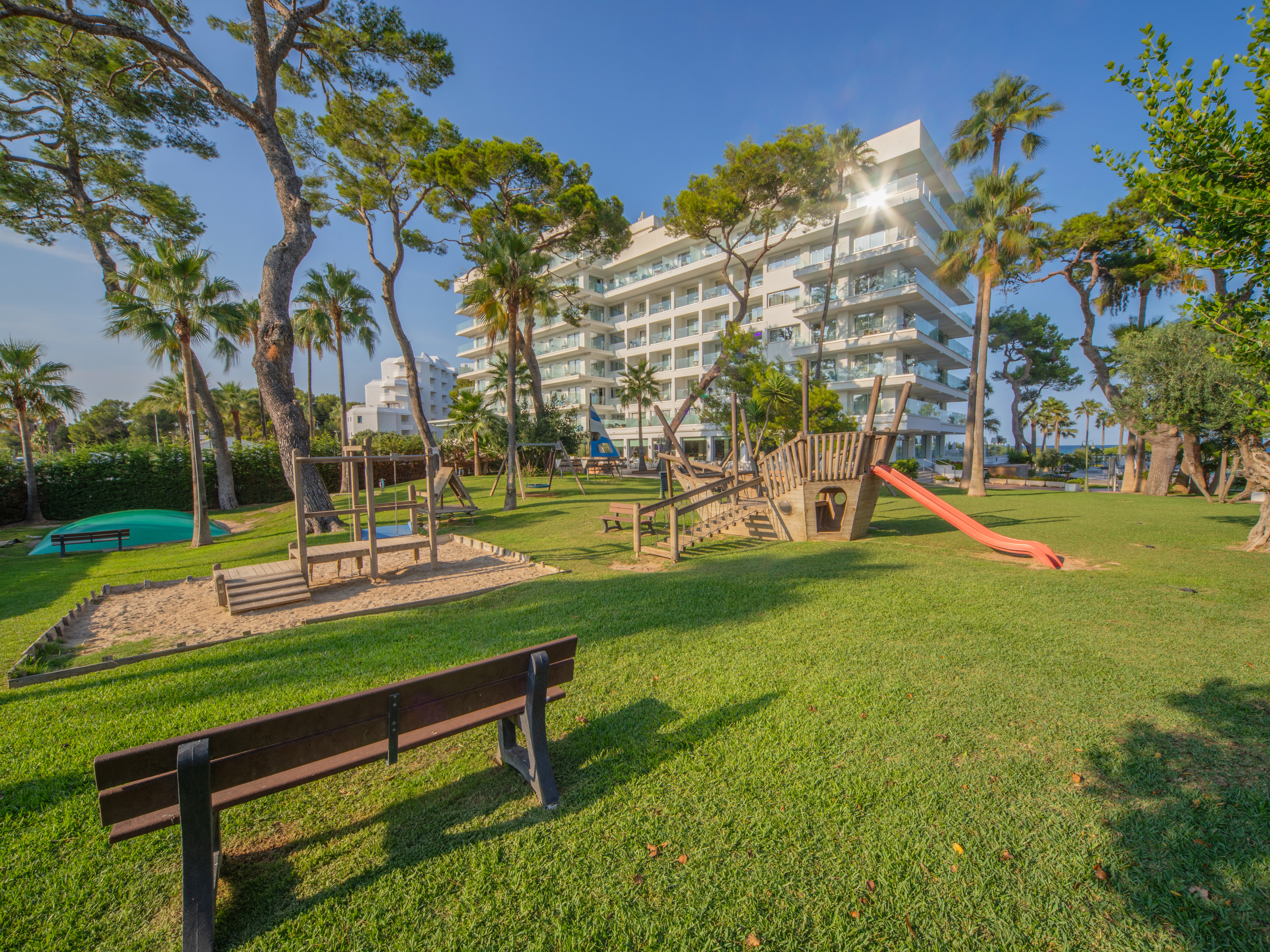 a playground in a park with trees and buildings in the background