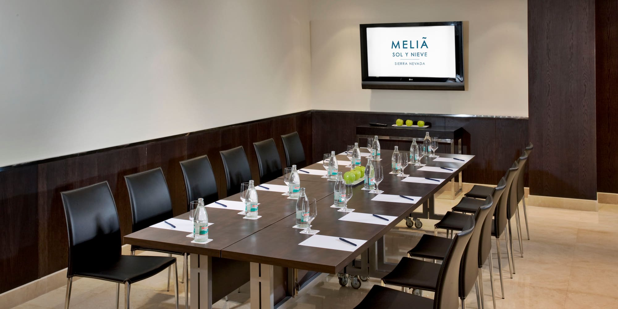 a long conference table with chairs and a screen