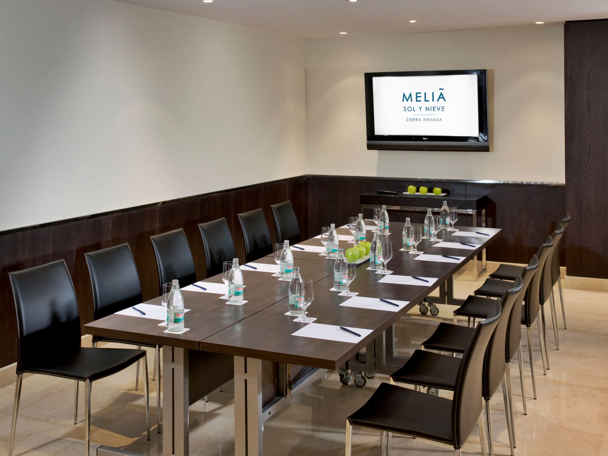a long conference table with chairs and a screen