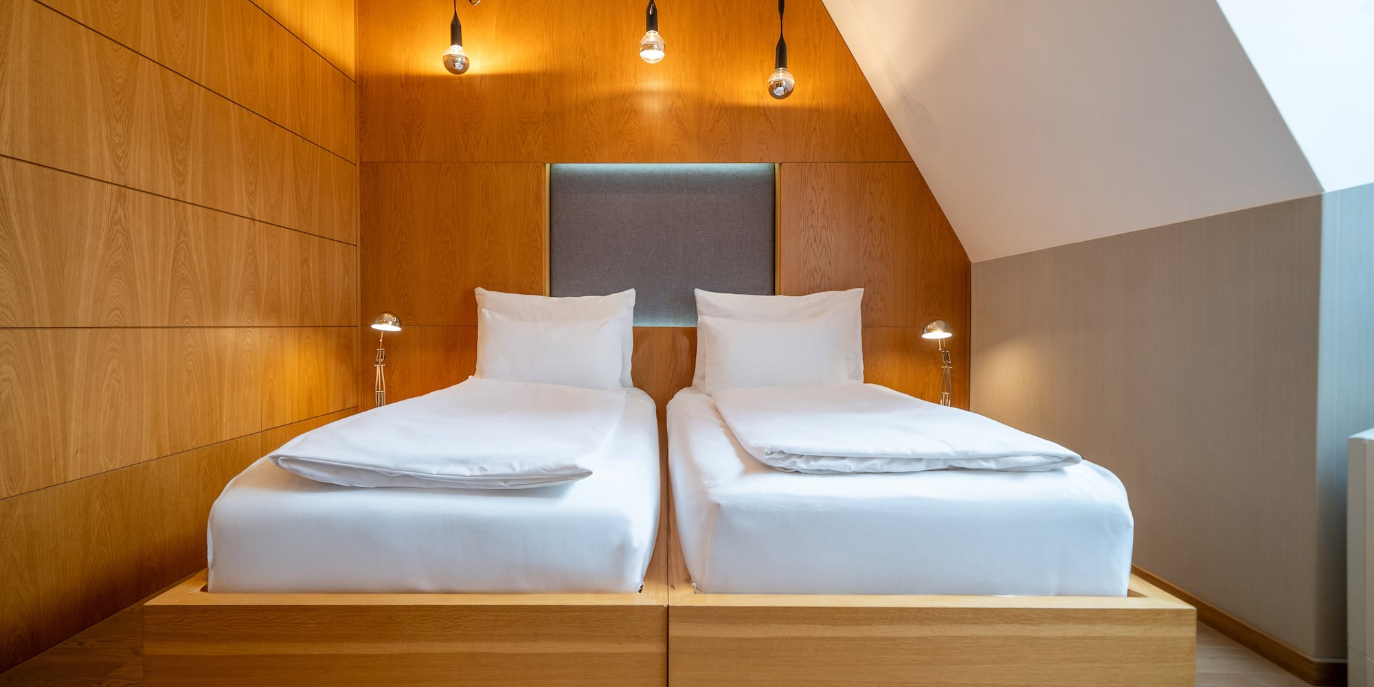 a two beds with white sheets and a wood paneled wall