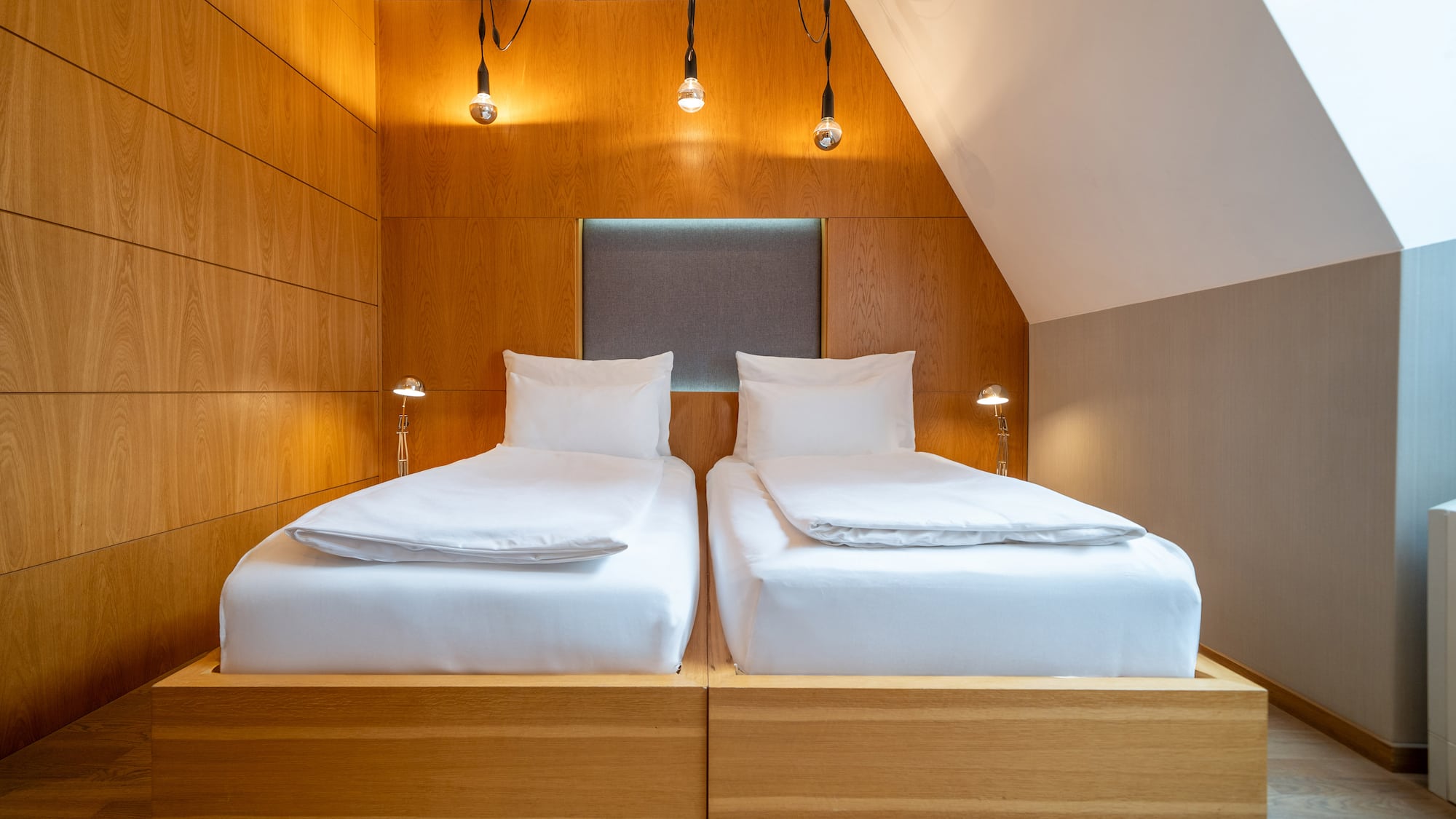 a two beds with white sheets and a wood paneled wall