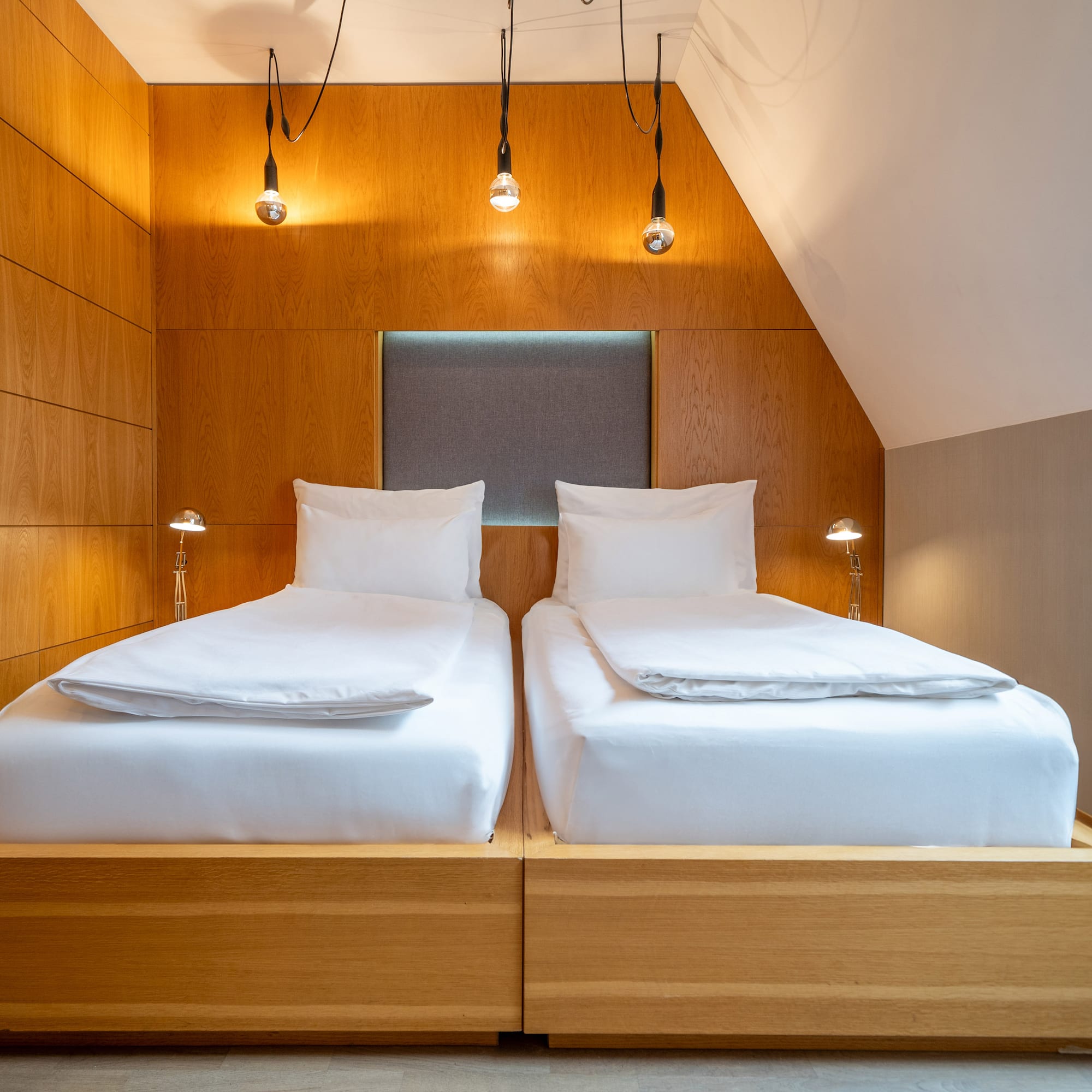 a two beds with white sheets and a wood paneled wall