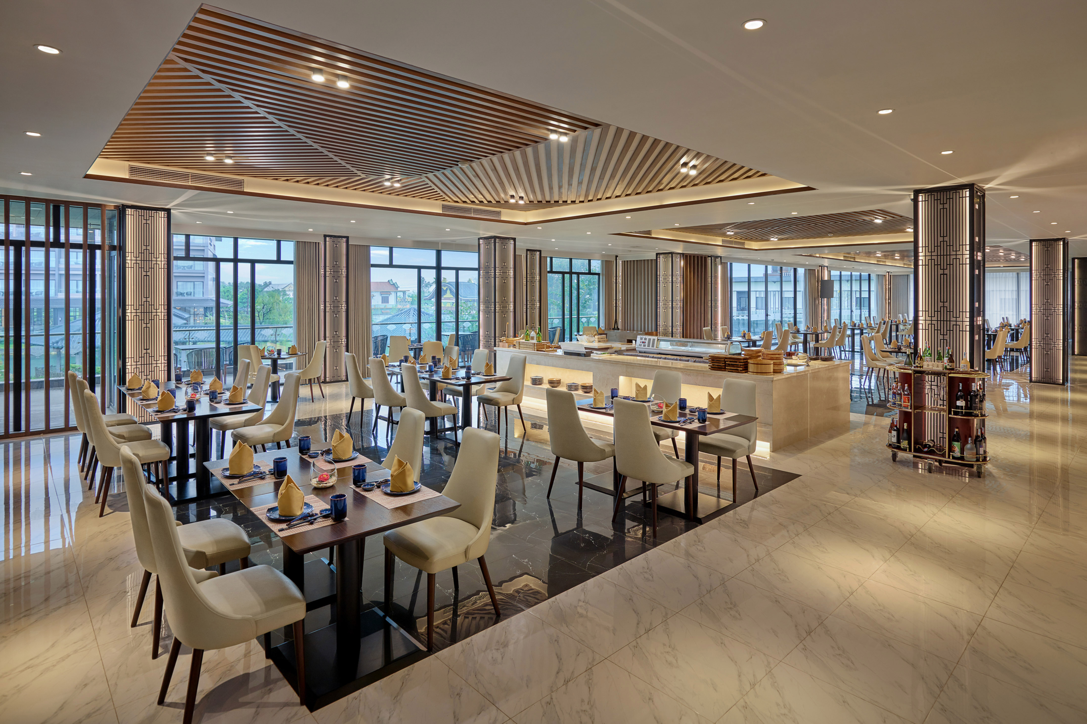 Modern hotel restaurant with buffet, elegant dining tables, and window views.