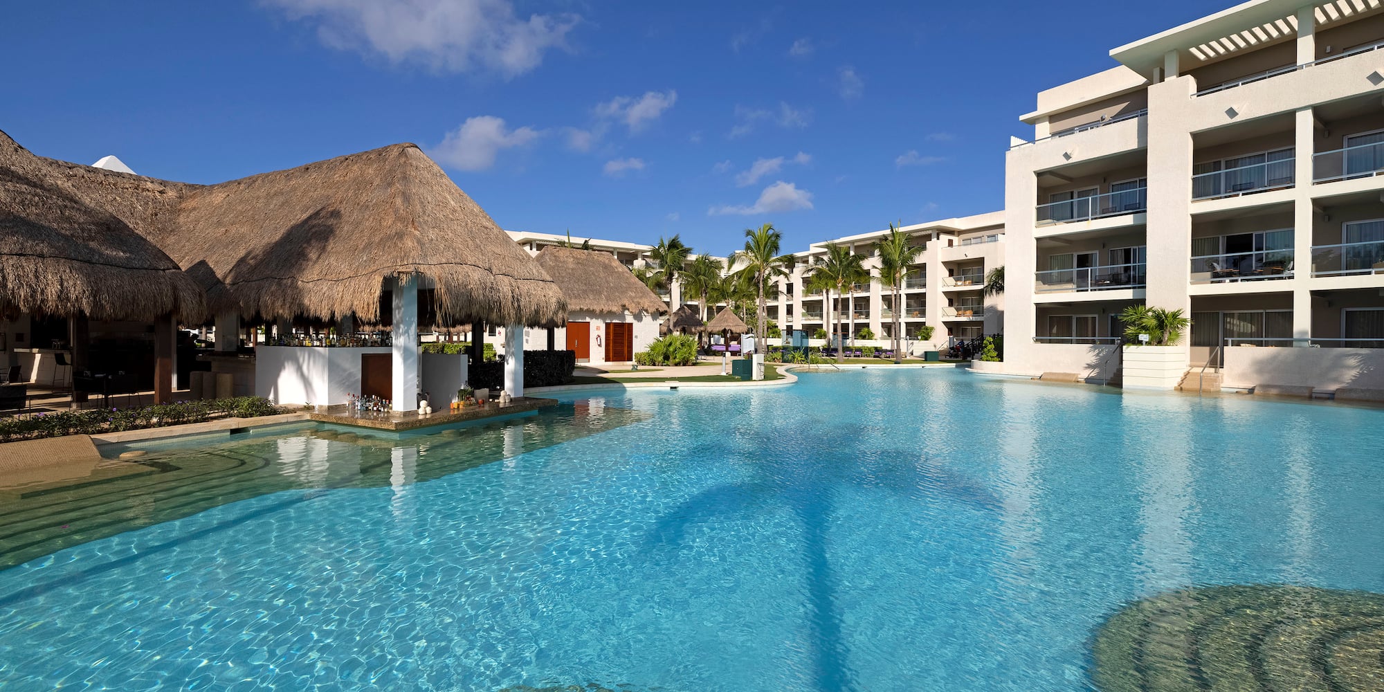 a pool with a thatched roof and buildings