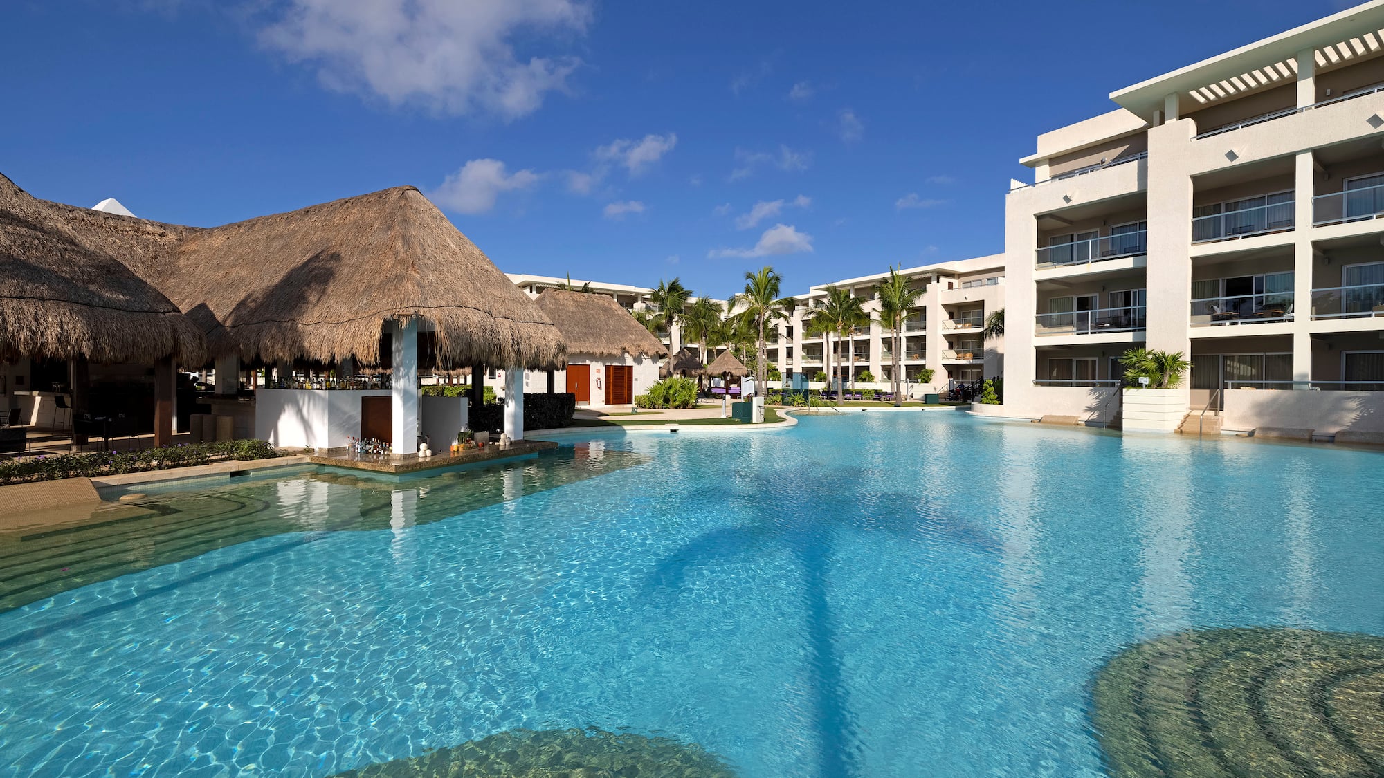 a pool with a thatched roof and buildings