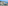 Sunny beach resort town with hotels, sandy beach, clear blue sea, and mountains.