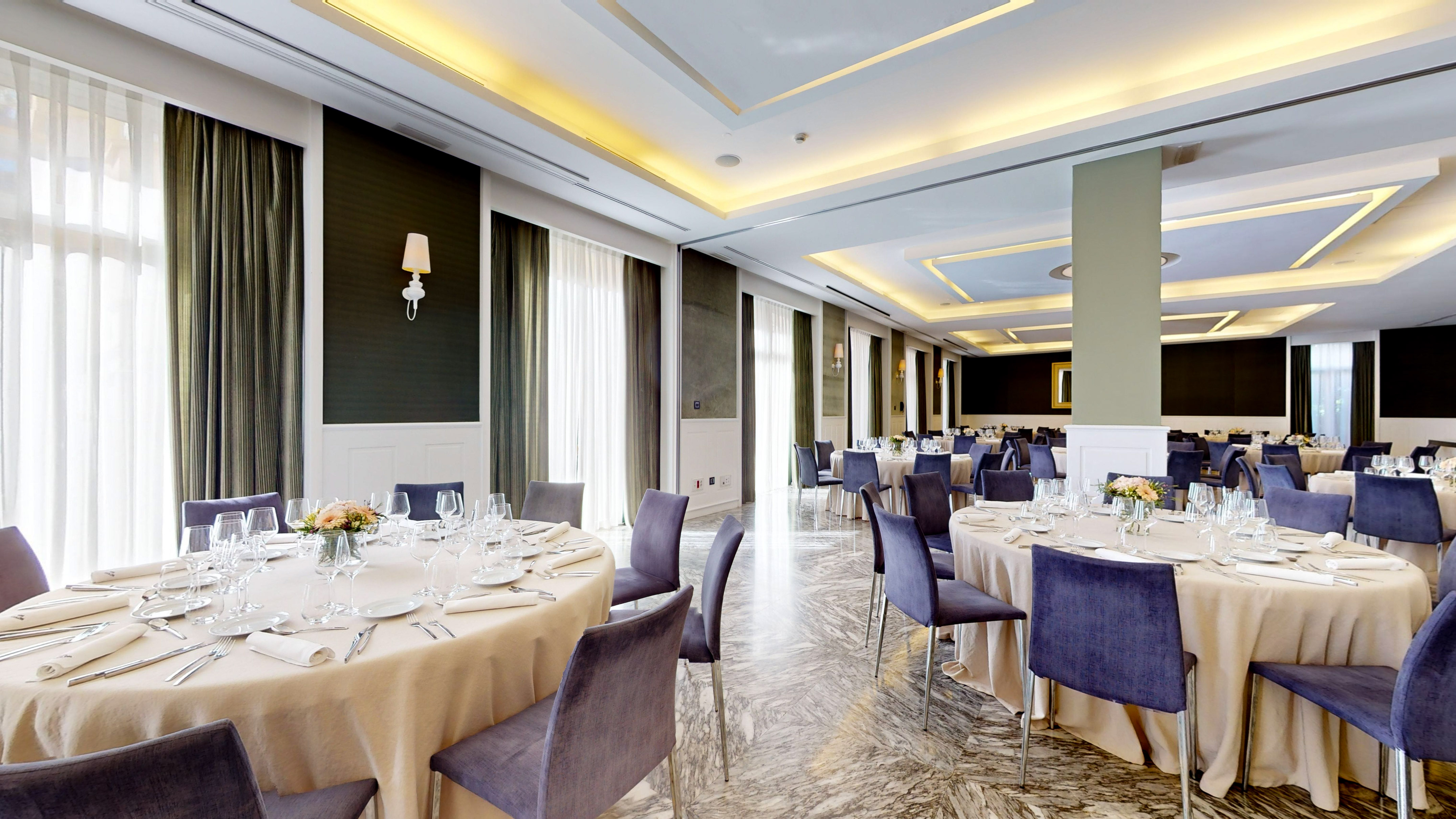 Elegant hotel banquet hall with formal dining tables and velvet chairs.