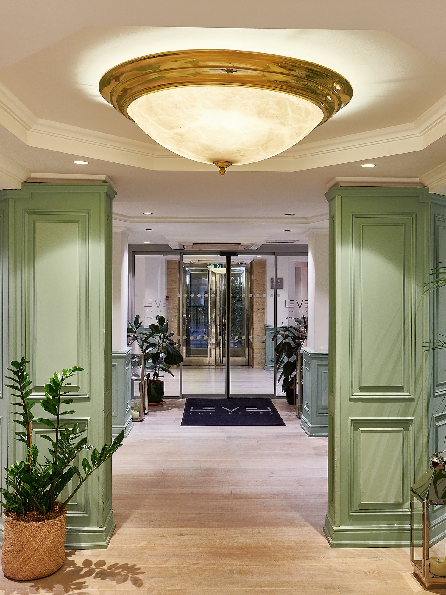 a hallway with green columns and plants