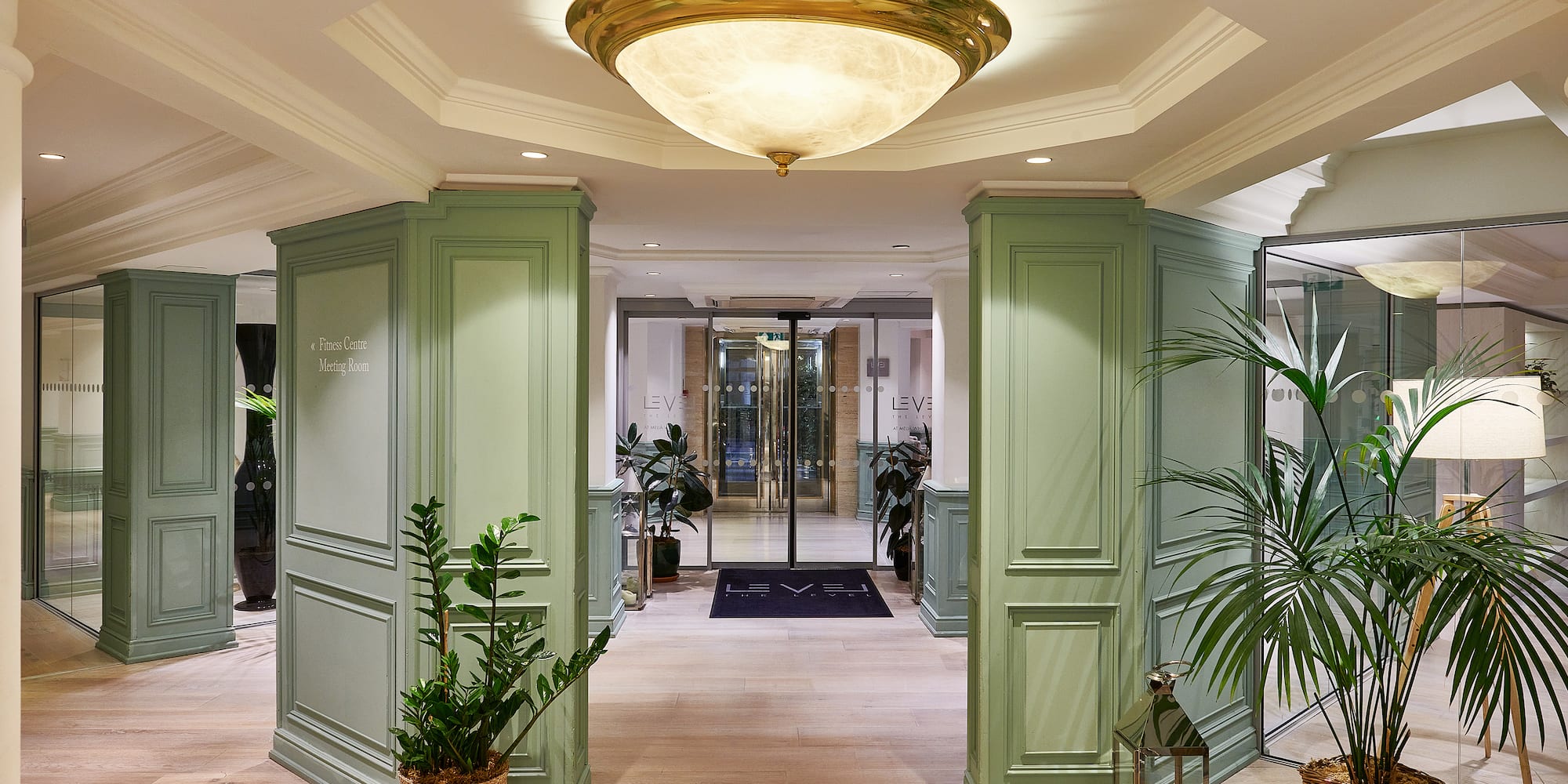 a hallway with green columns and plants