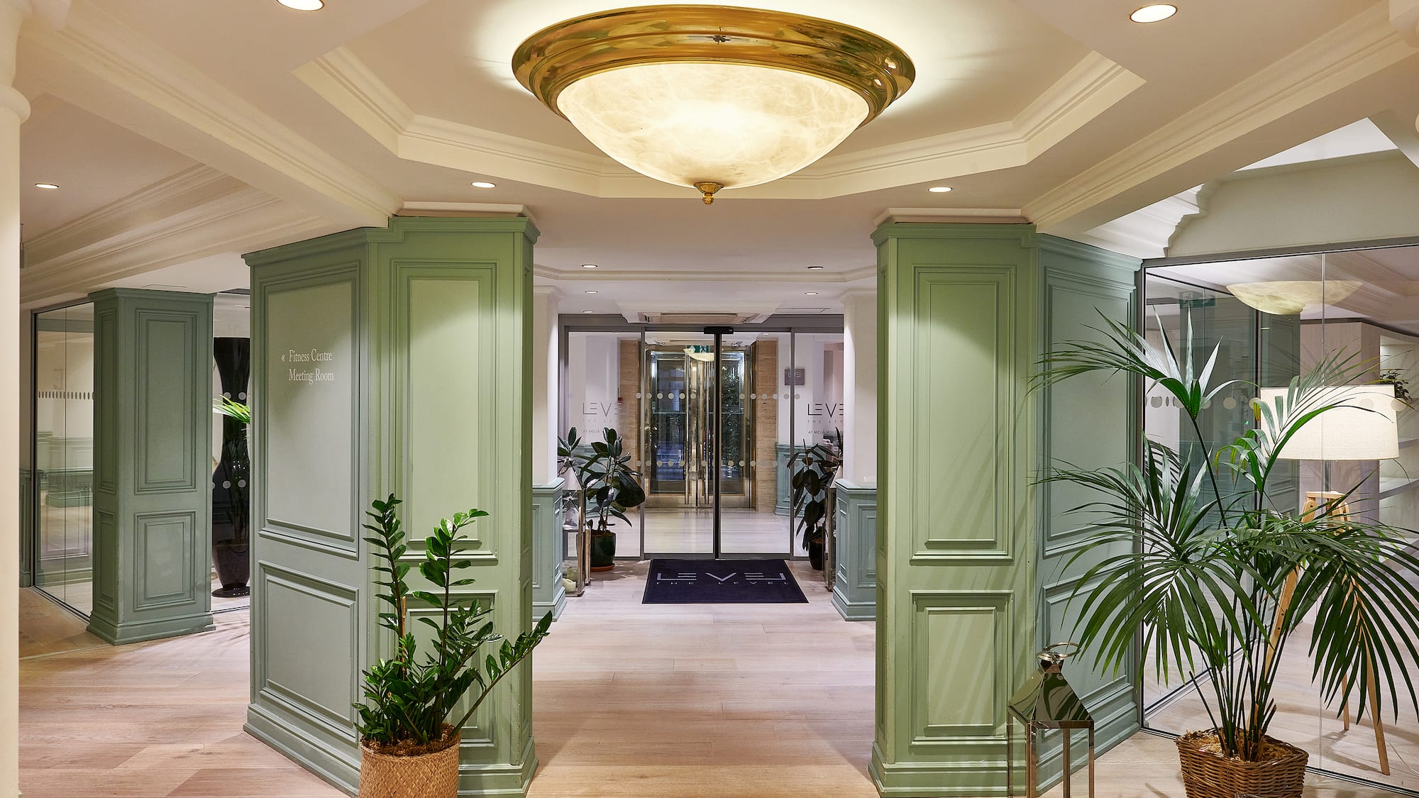 a hallway with green columns and plants