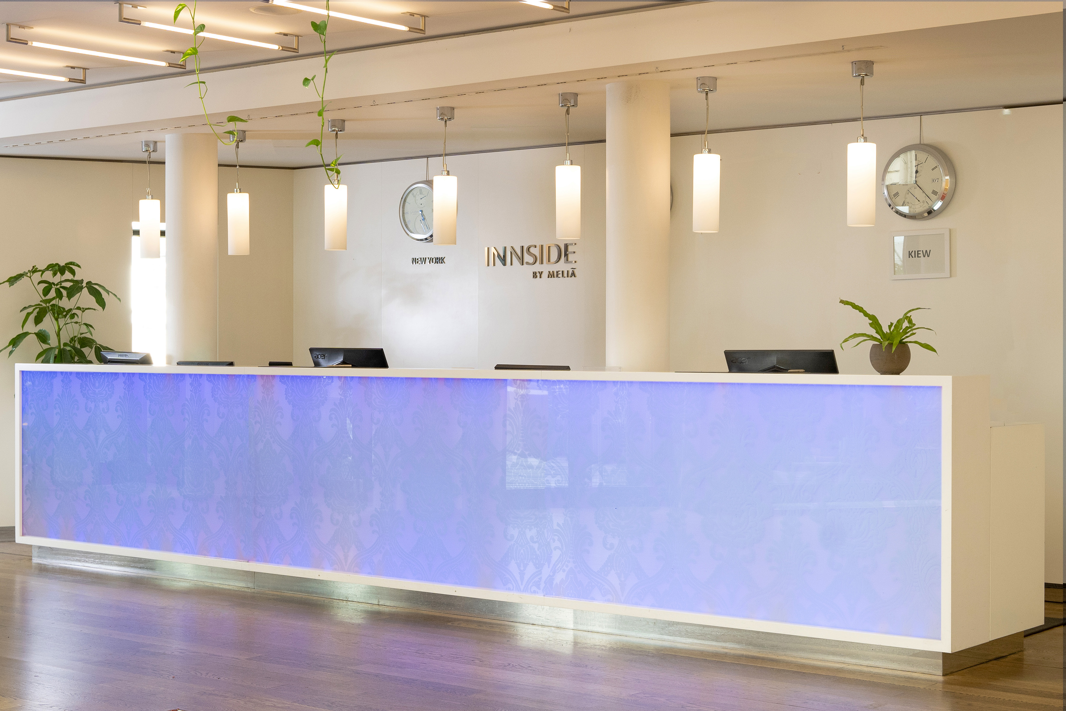 Modern Innside by Meliá hotel lobby with glowing reception desk and clocks.
