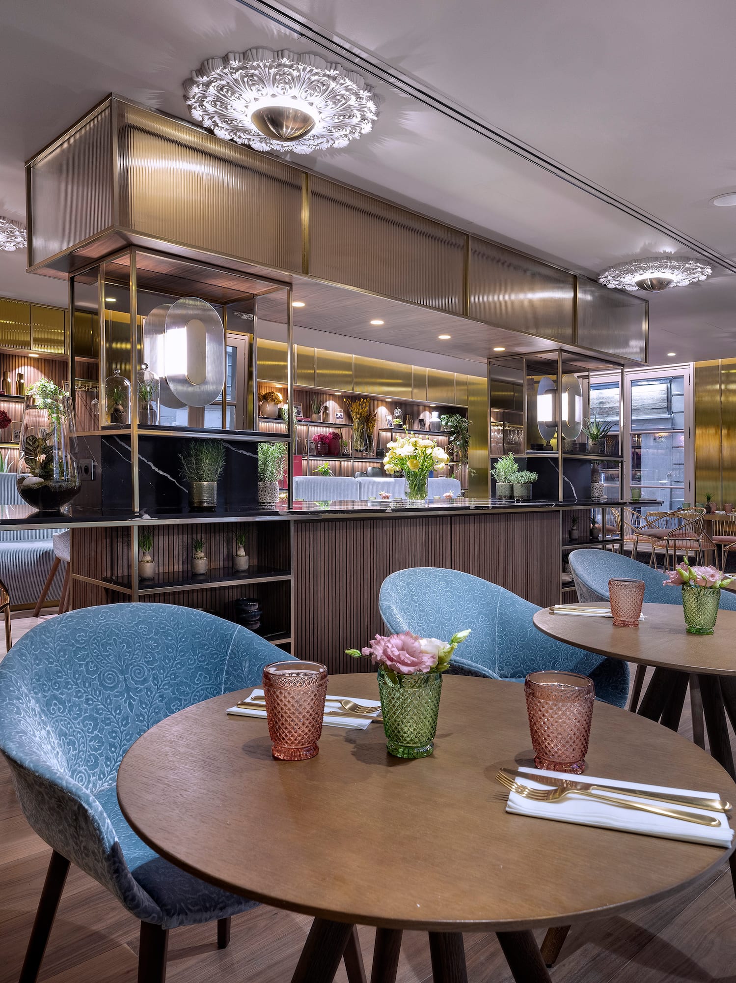 Elegant restaurant dining area with blue chairs, wooden tables, and a chic bar.