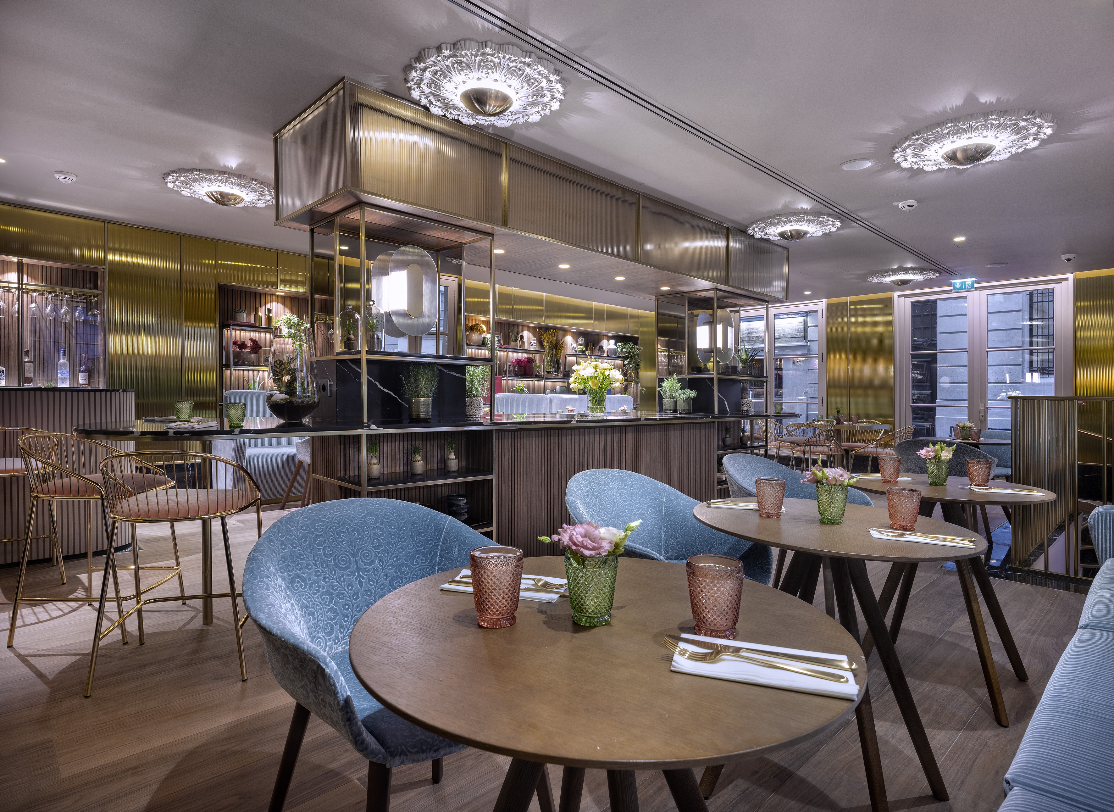 Elegant restaurant dining area with blue chairs, wooden tables, and a chic bar.