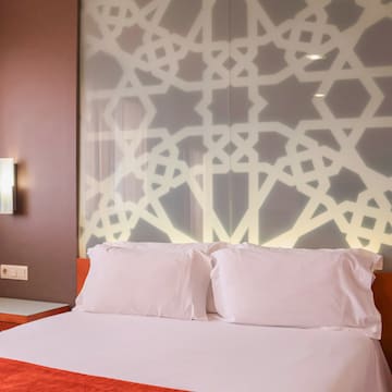 a bed with white pillows and a wall with a light on it