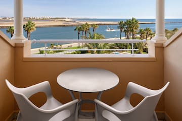 a table and chairs on a balcony overlooking a body of water