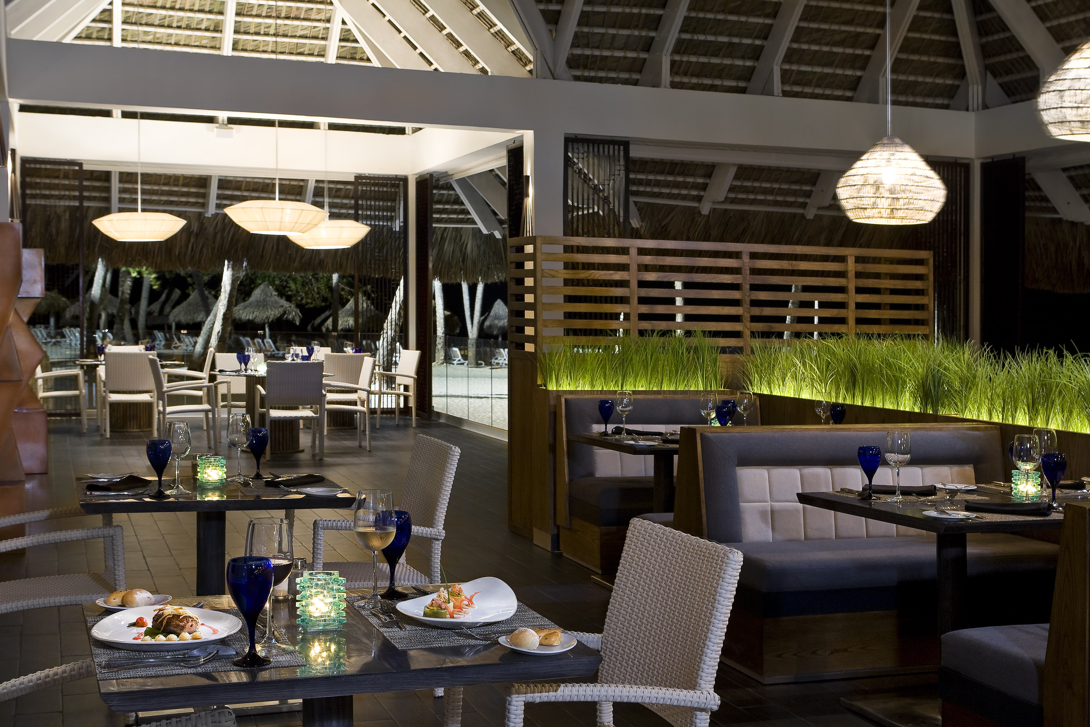 Upscale tropical restaurant with set tables, ambient lighting, and outdoor view.