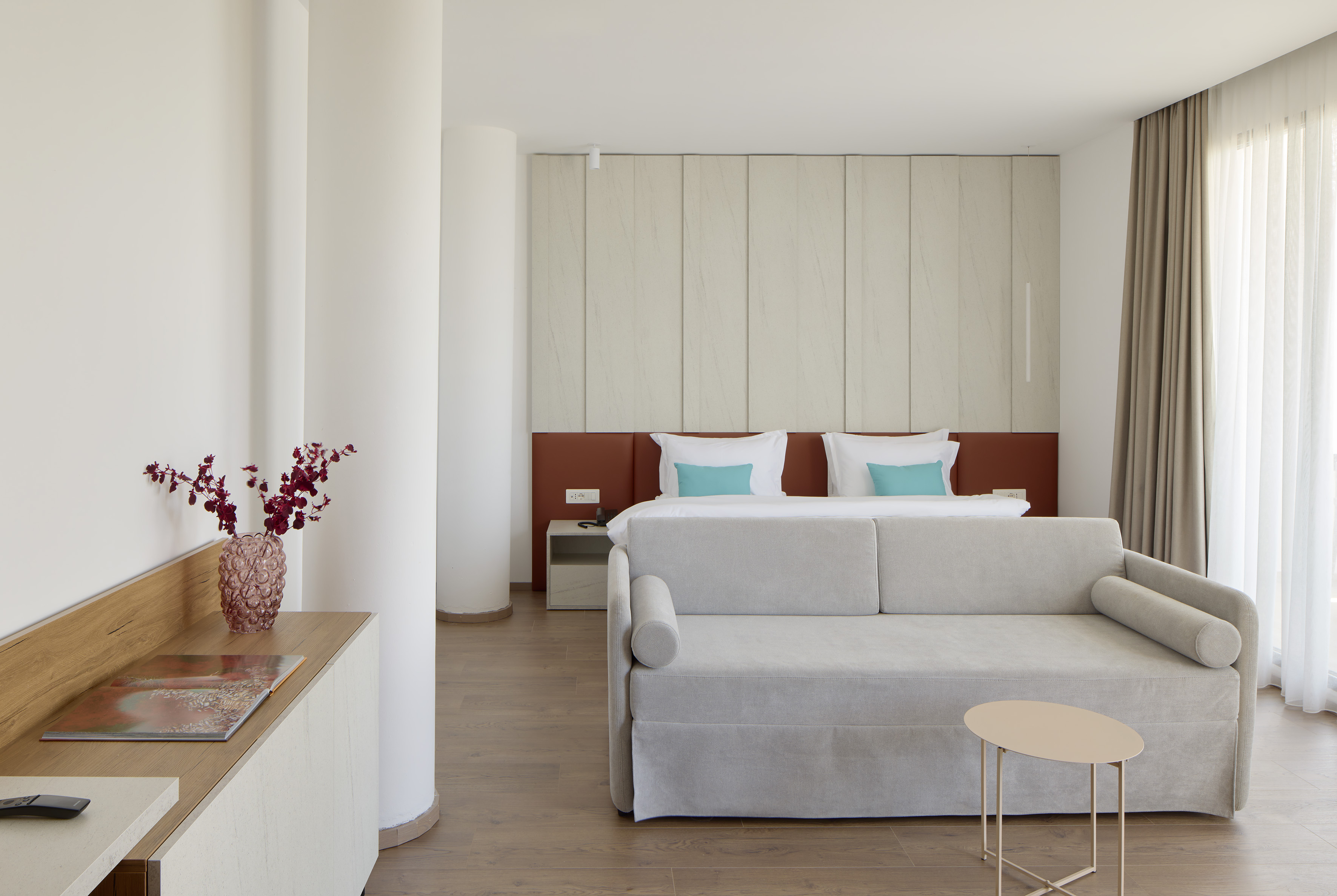 Contemporary hotel room featuring a bed, pull-out sofa, and wood floor.