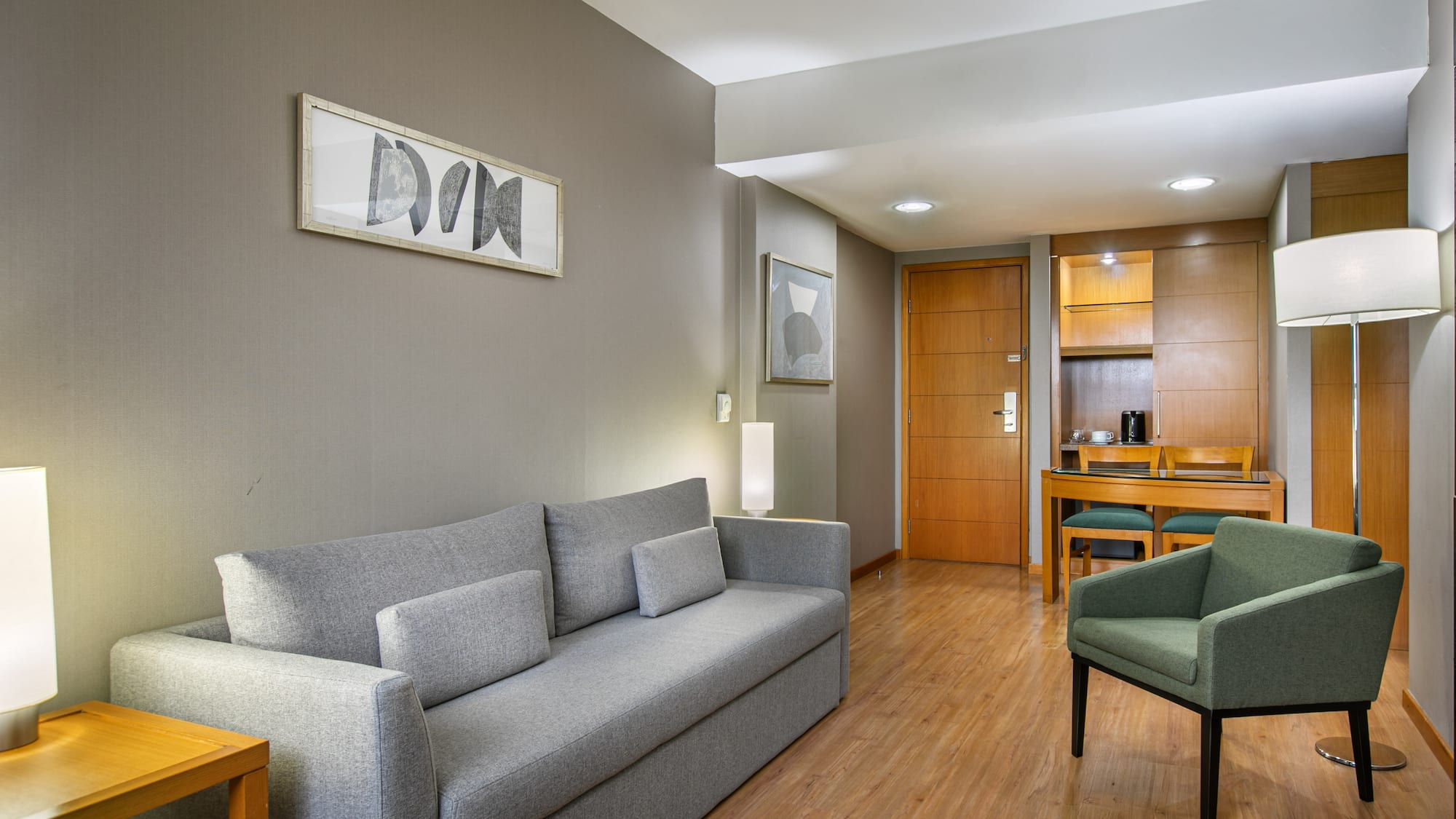 Modern living area with gray sofa, green accent chair, wood floor, and dining nook.