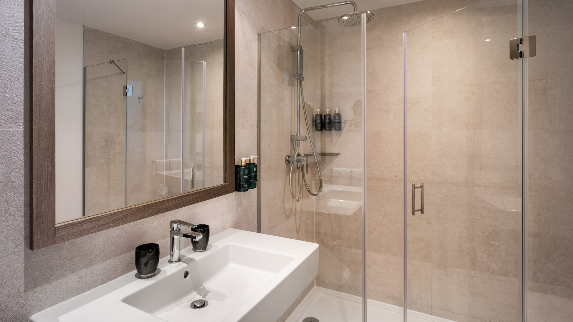 Modern bathroom with white sink, framed mirror, and glass walk-in shower.