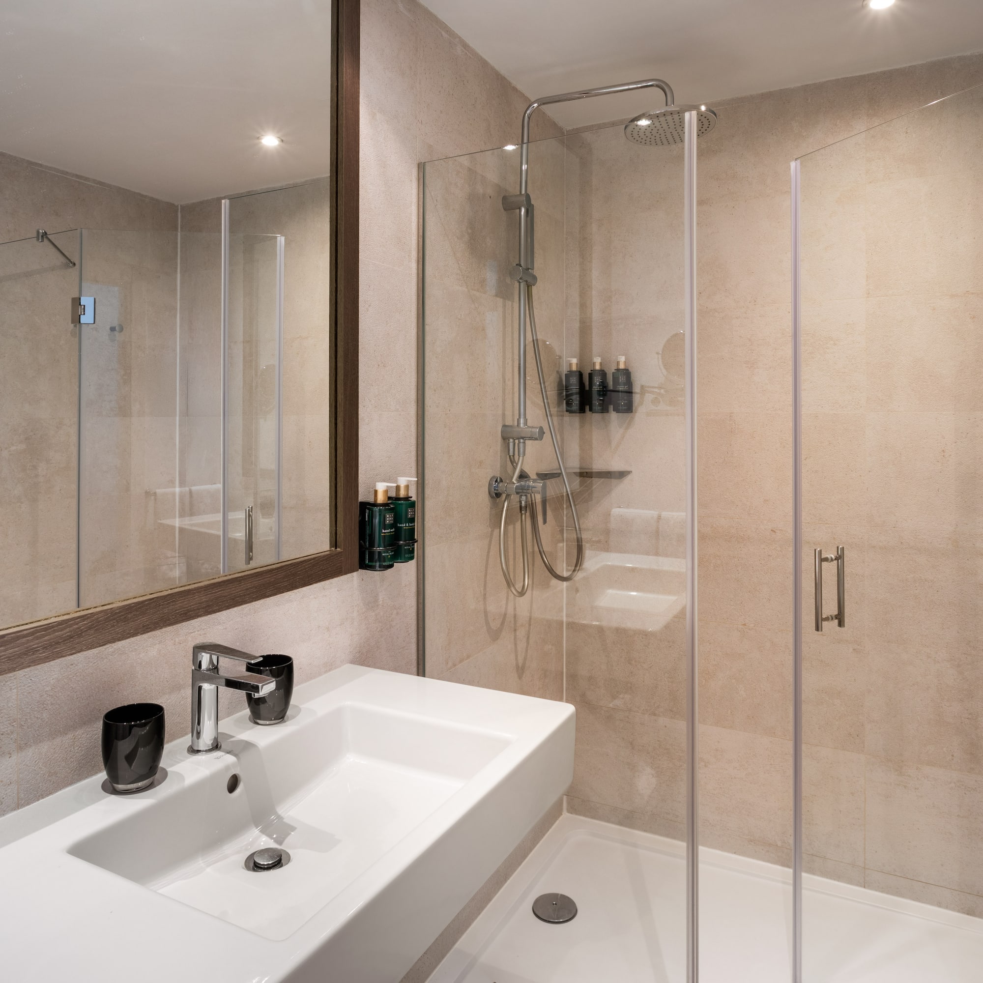 Modern bathroom with white sink, framed mirror, and glass walk-in shower.