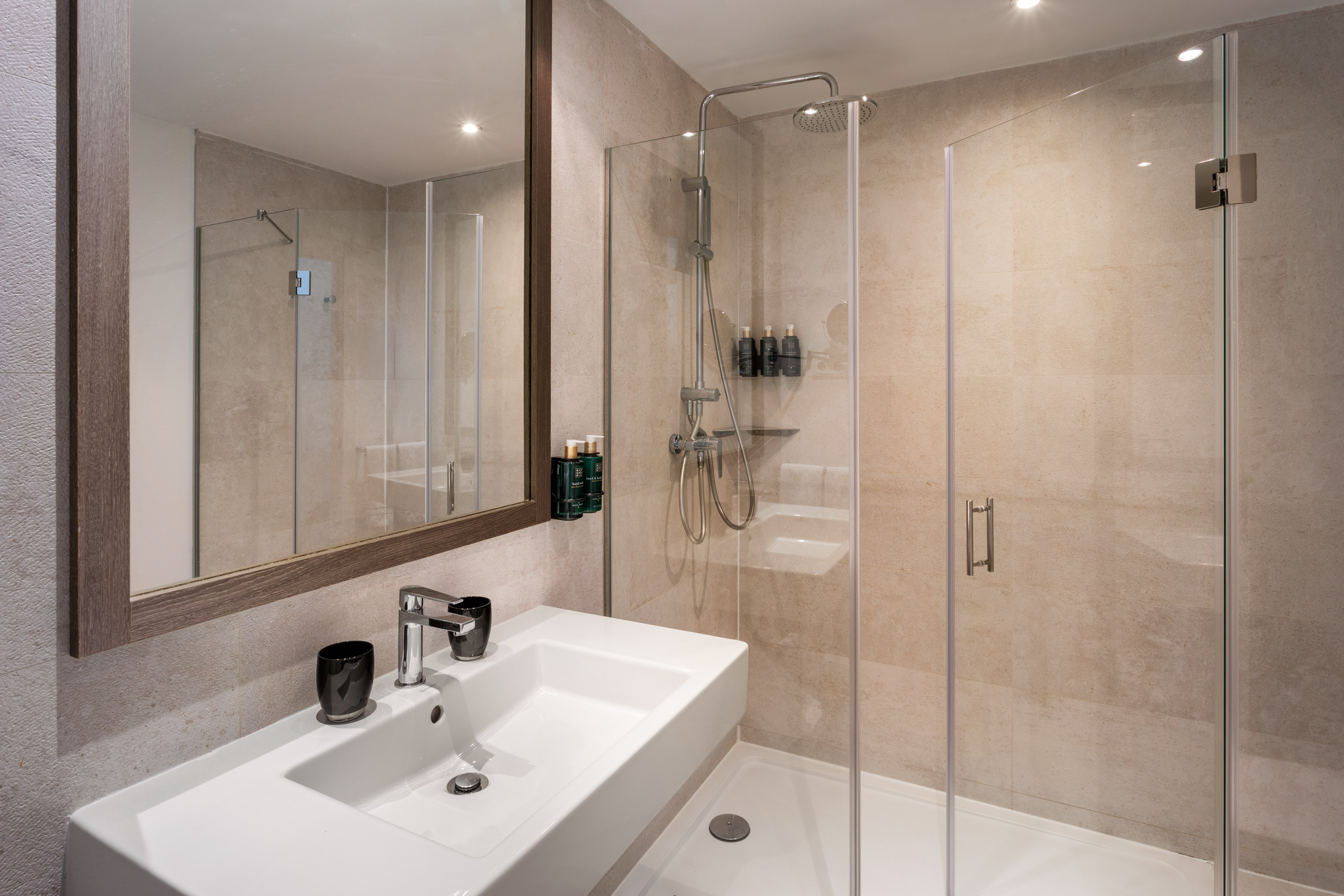 Modern bathroom with white sink, framed mirror, and glass walk-in shower.
