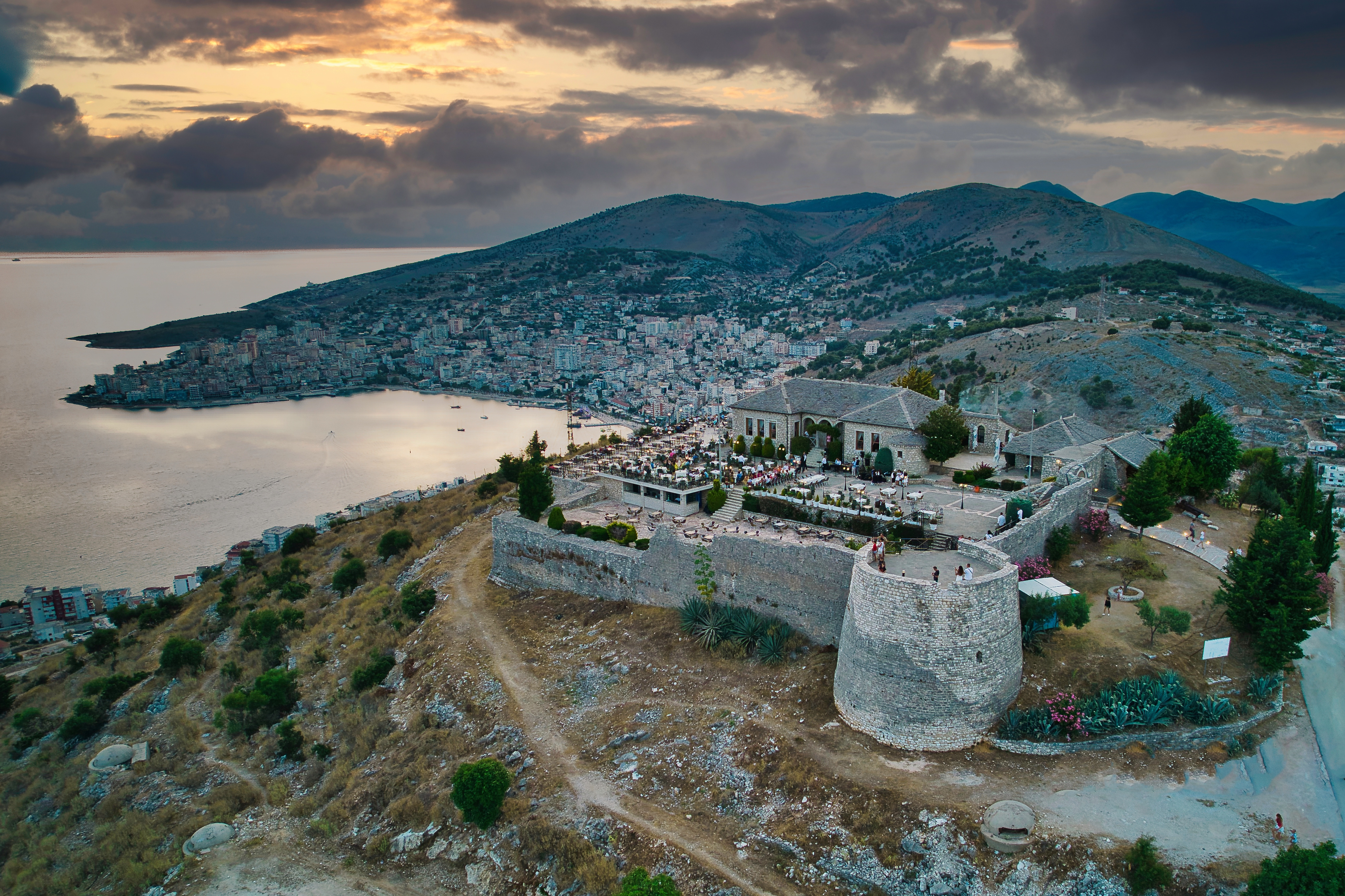 a stone building on a hill with a body of water in the background