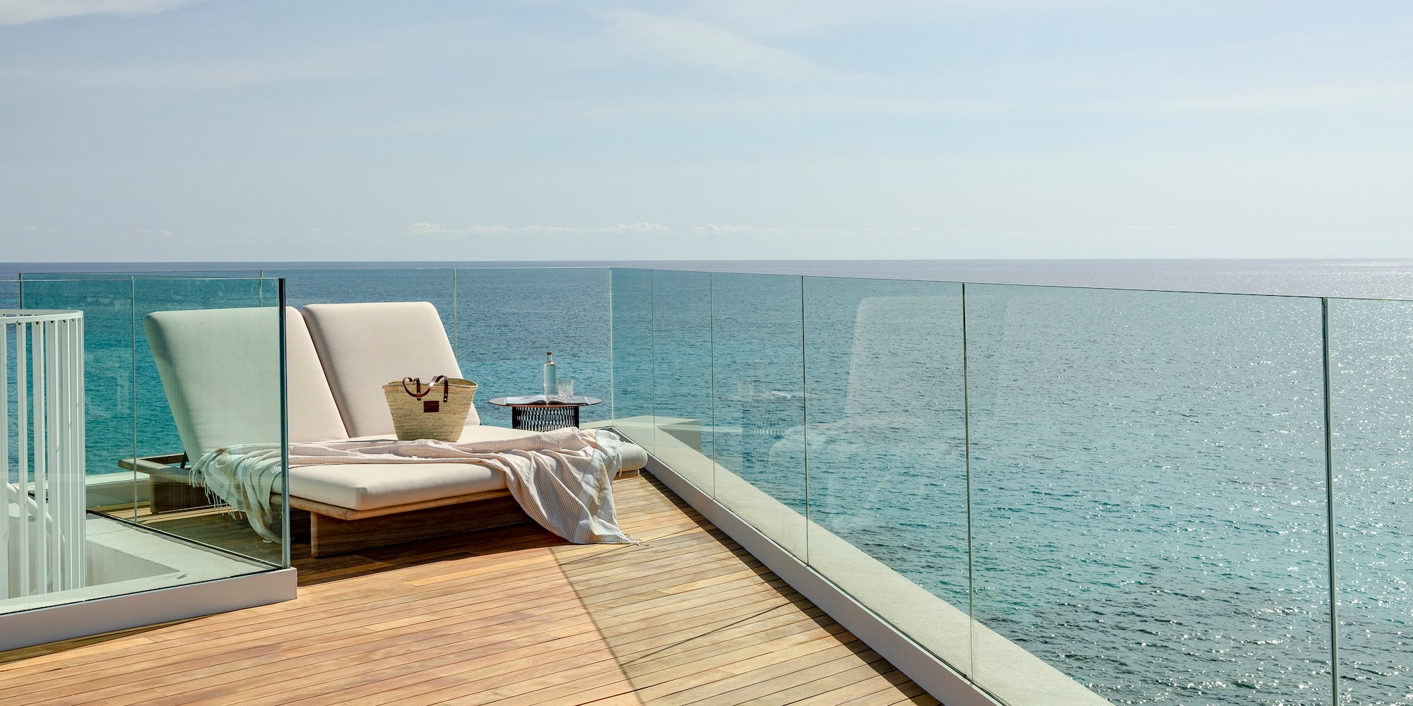 a deck with a chair and a blanket on it overlooking the ocean