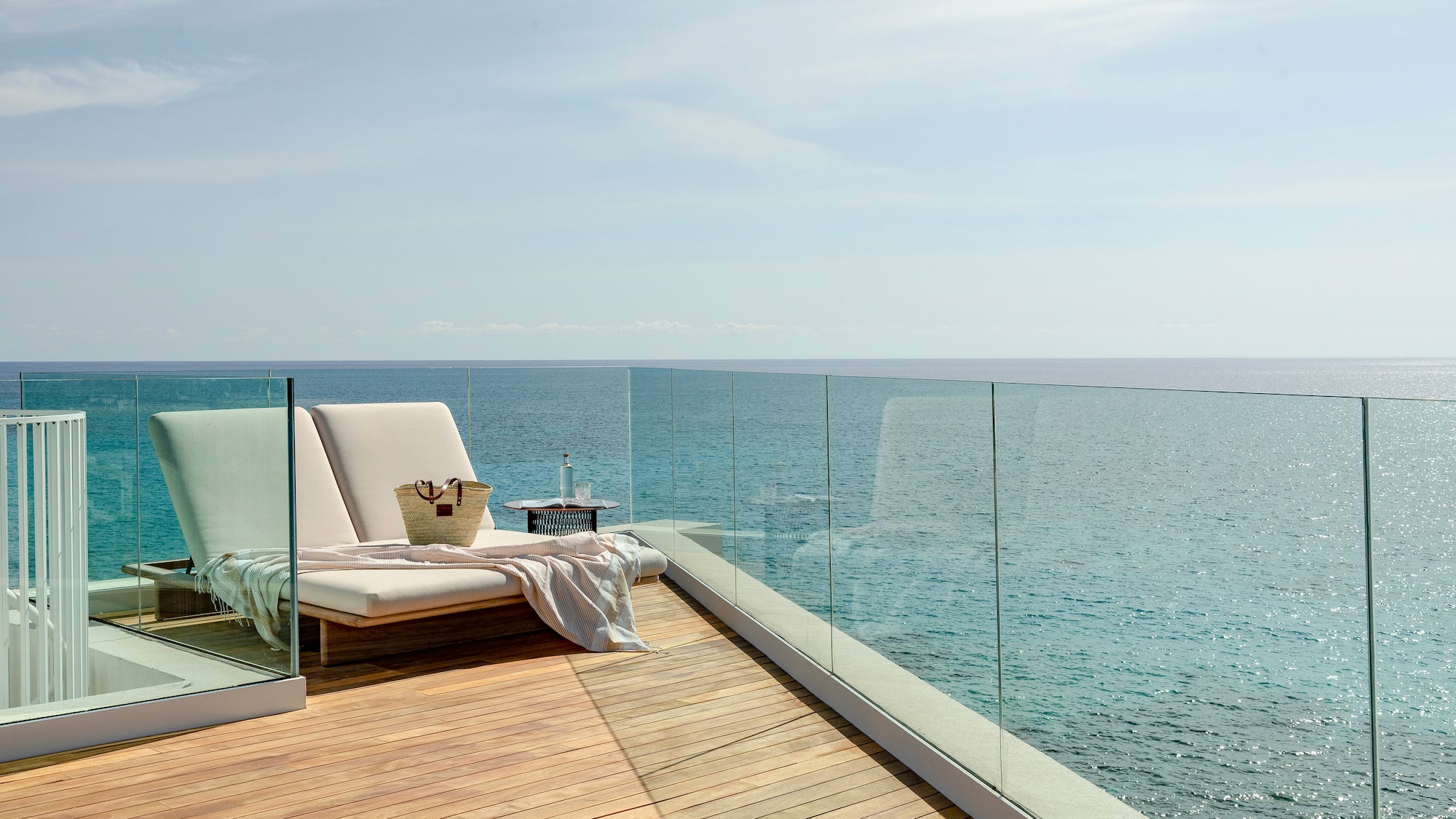 a deck with a chair and a blanket on it overlooking the ocean