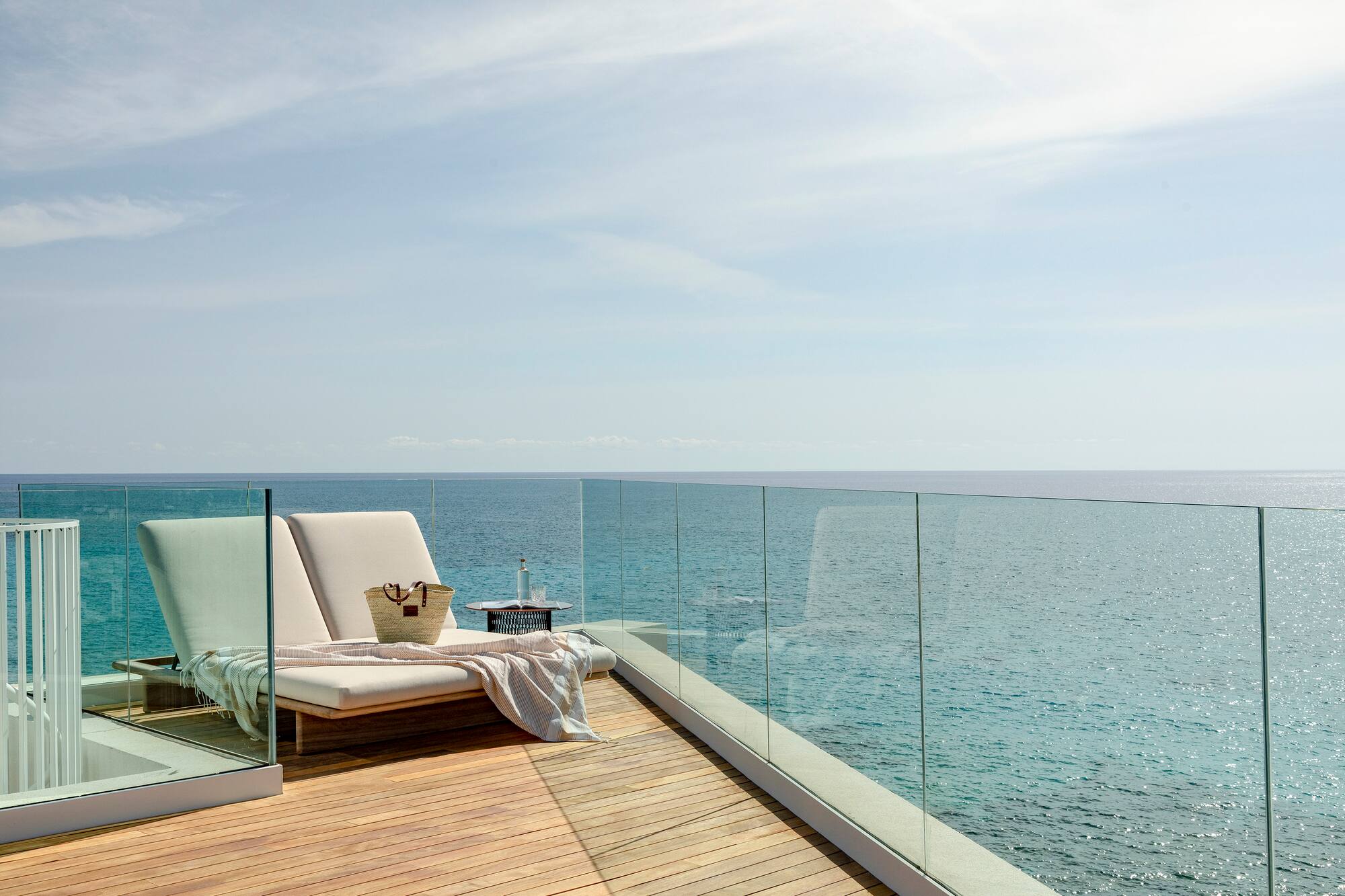 a deck with a chair and a blanket on it overlooking the ocean