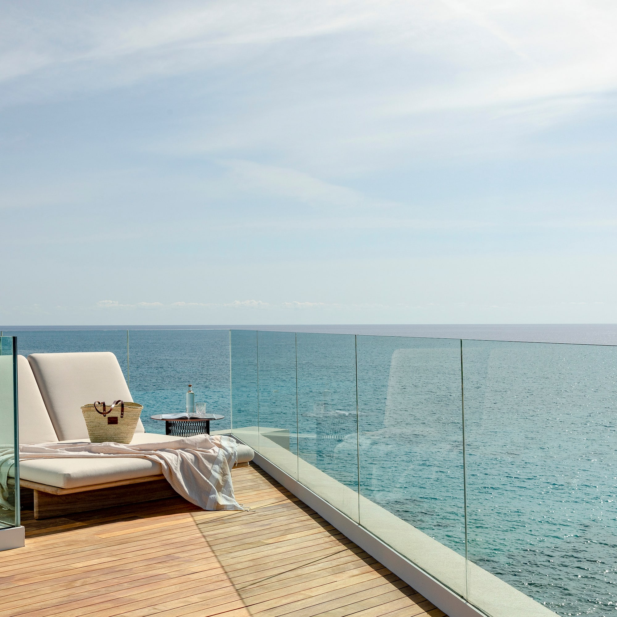 a deck with a chair and a blanket on it overlooking the ocean