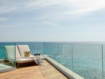 a deck with a chair and a blanket on it overlooking the ocean