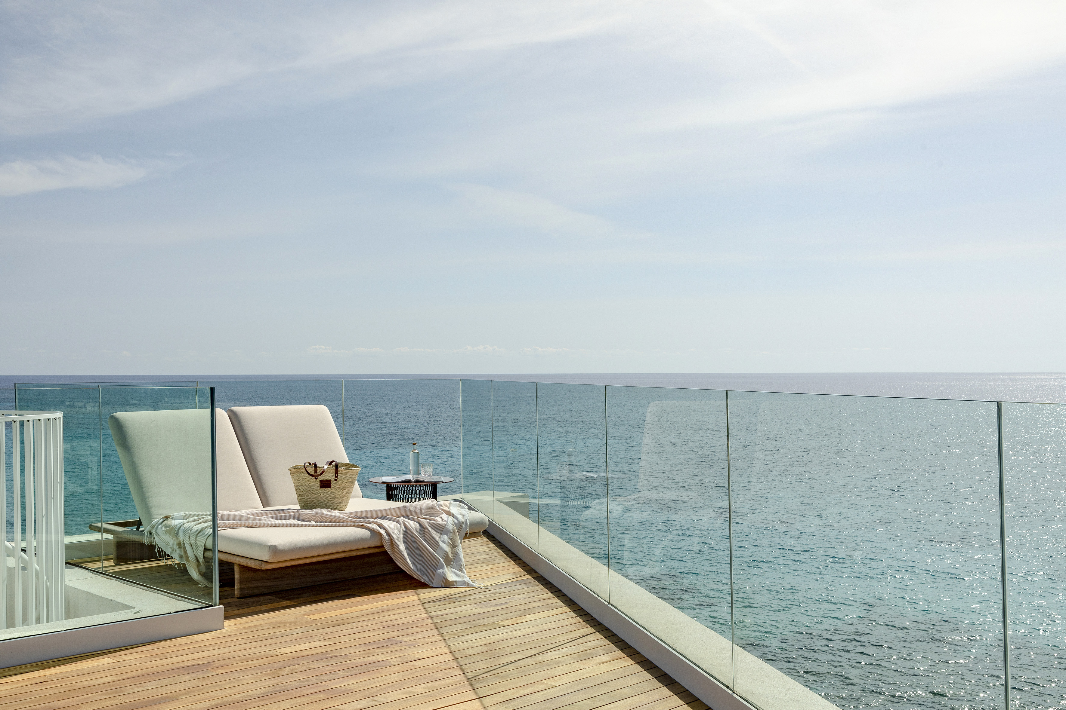 Oceanfront balcony with sun loungers, wooden deck, and stunning sea view.