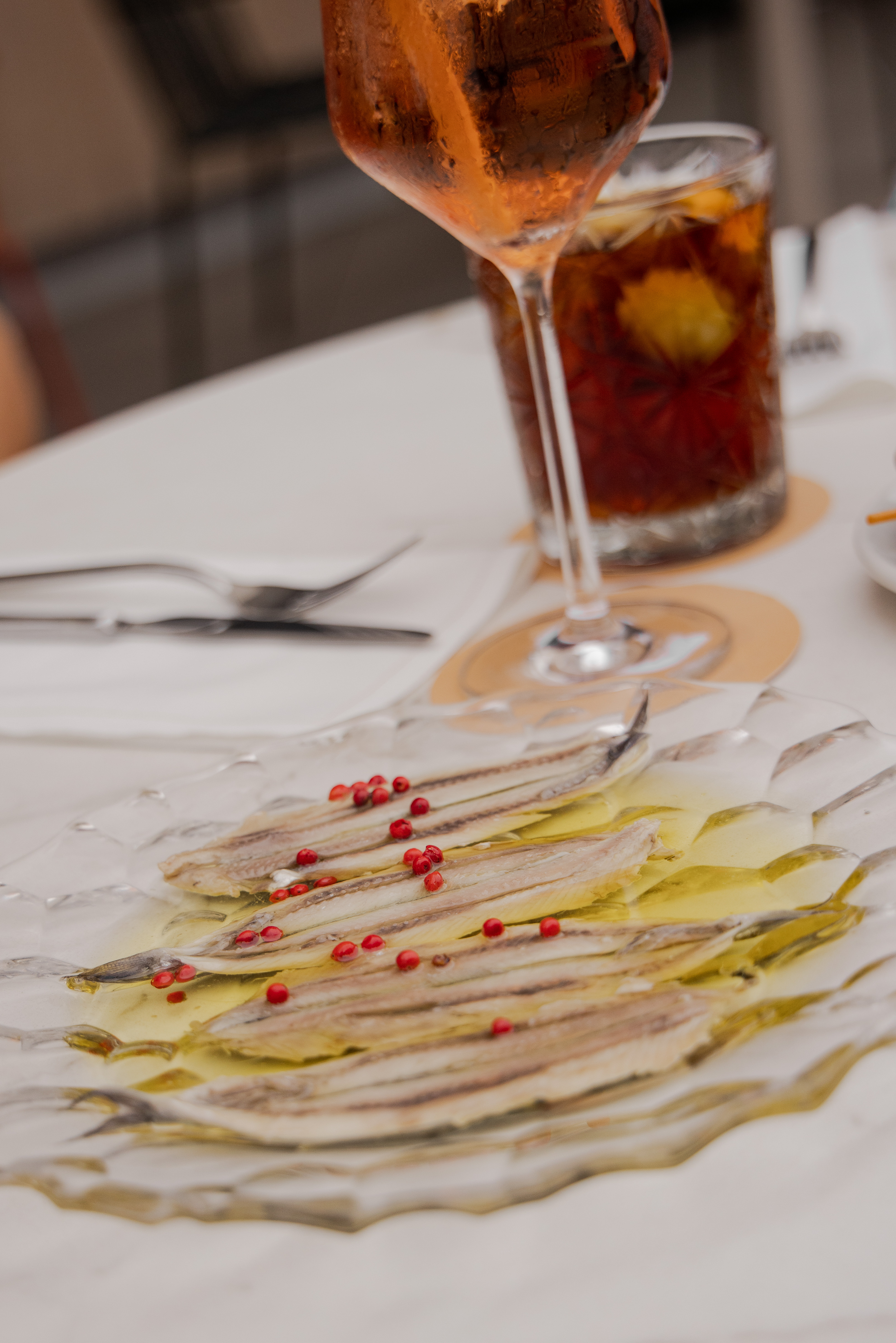 White anchovy fillets, red peppercorns, olive oil, with Aperol Spritz.