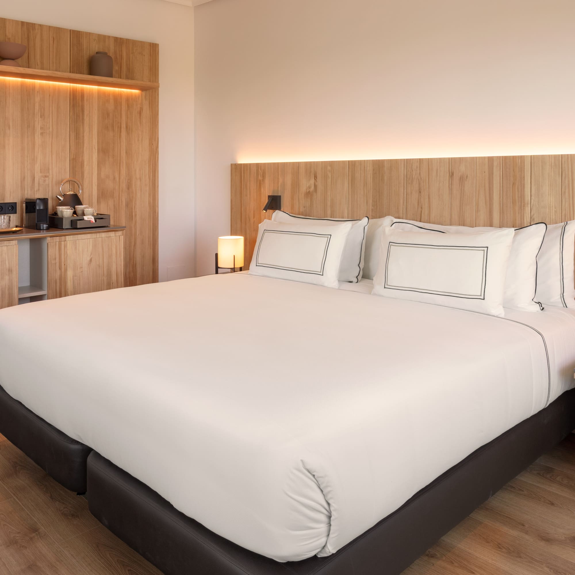 a bed with white sheets and a wood headboard
