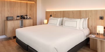 a bed with white sheets and a wood headboard