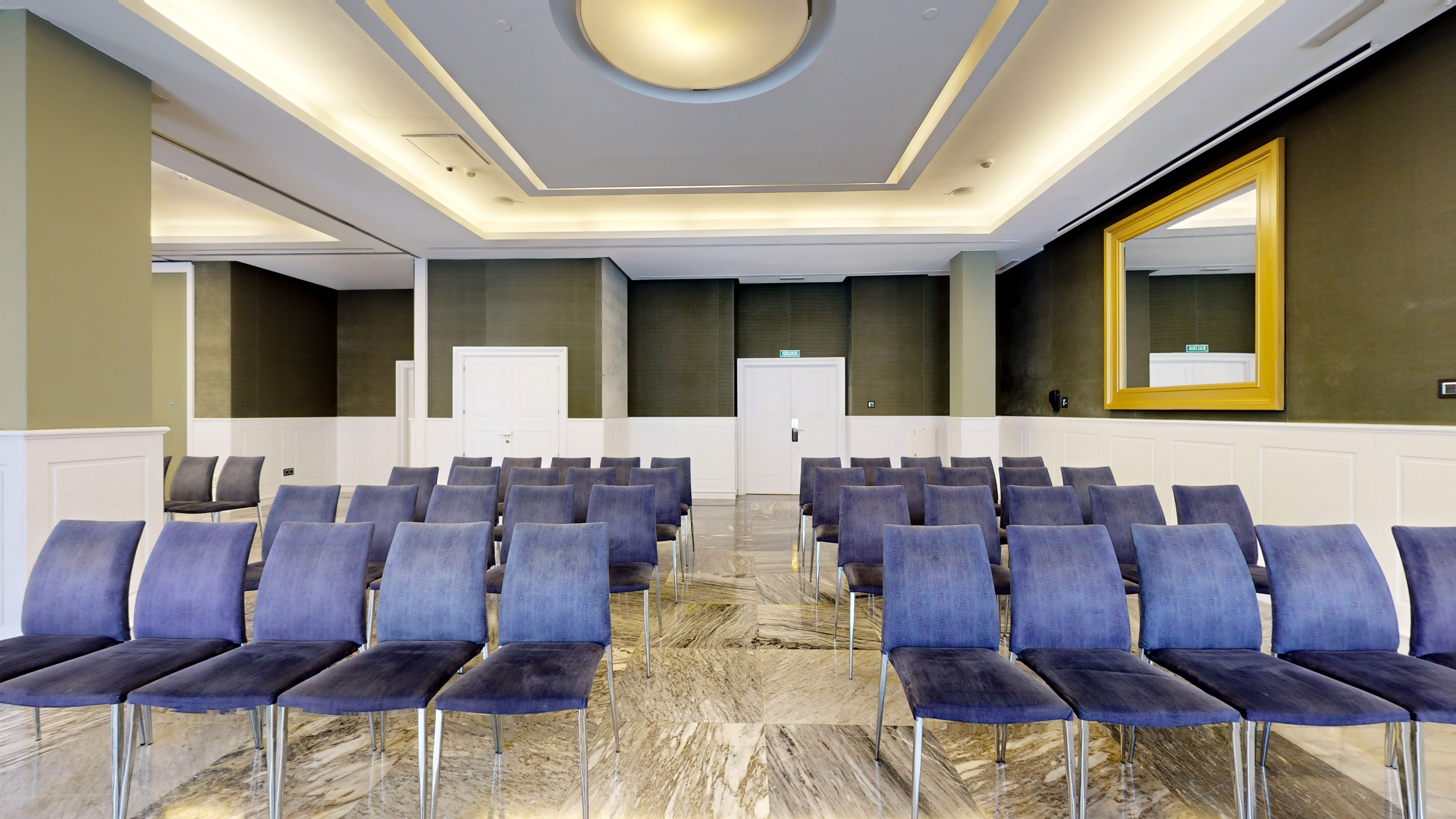 Spacious modern conference room with blue chairs, marble floor, and elegant lighting.