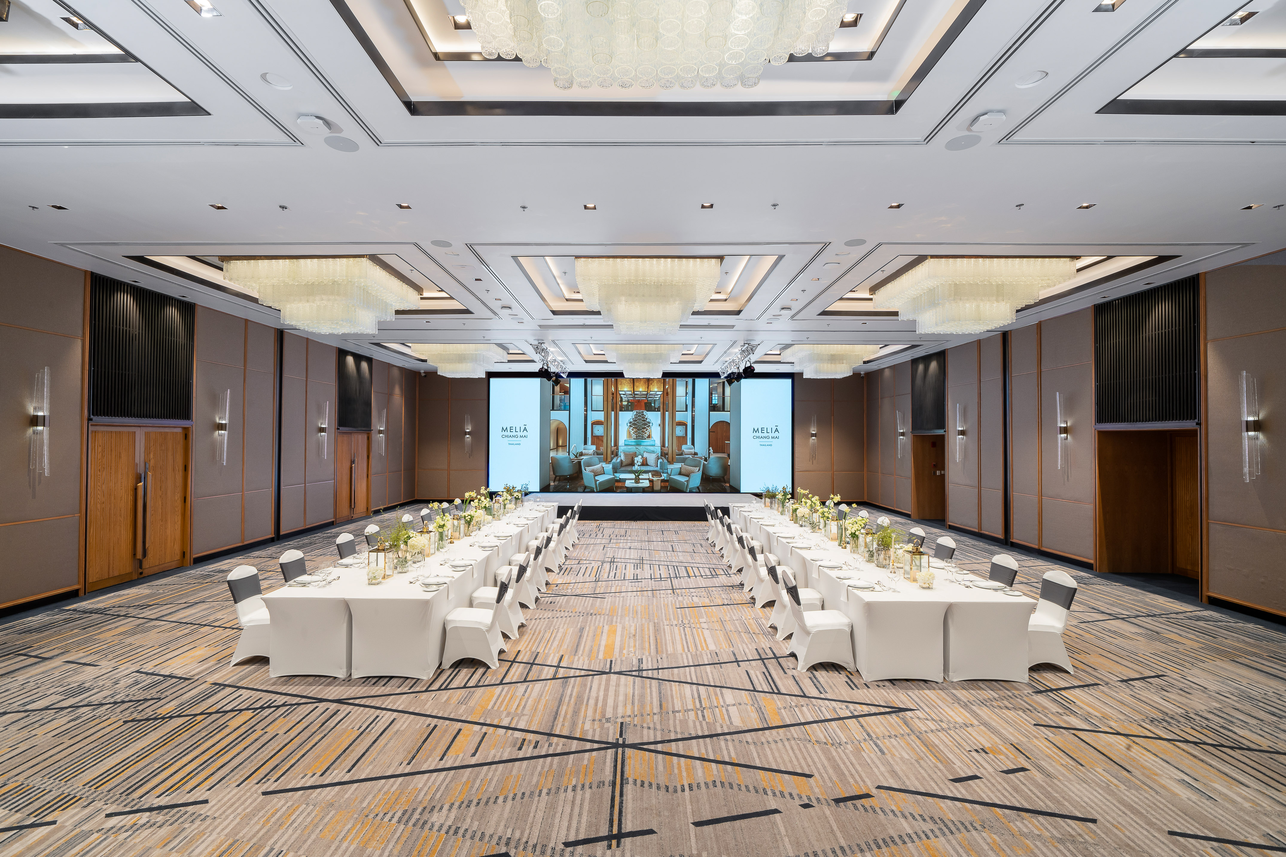 Meliá Chiang Mai hotel ballroom ready for an event with banquet tables and large screens.