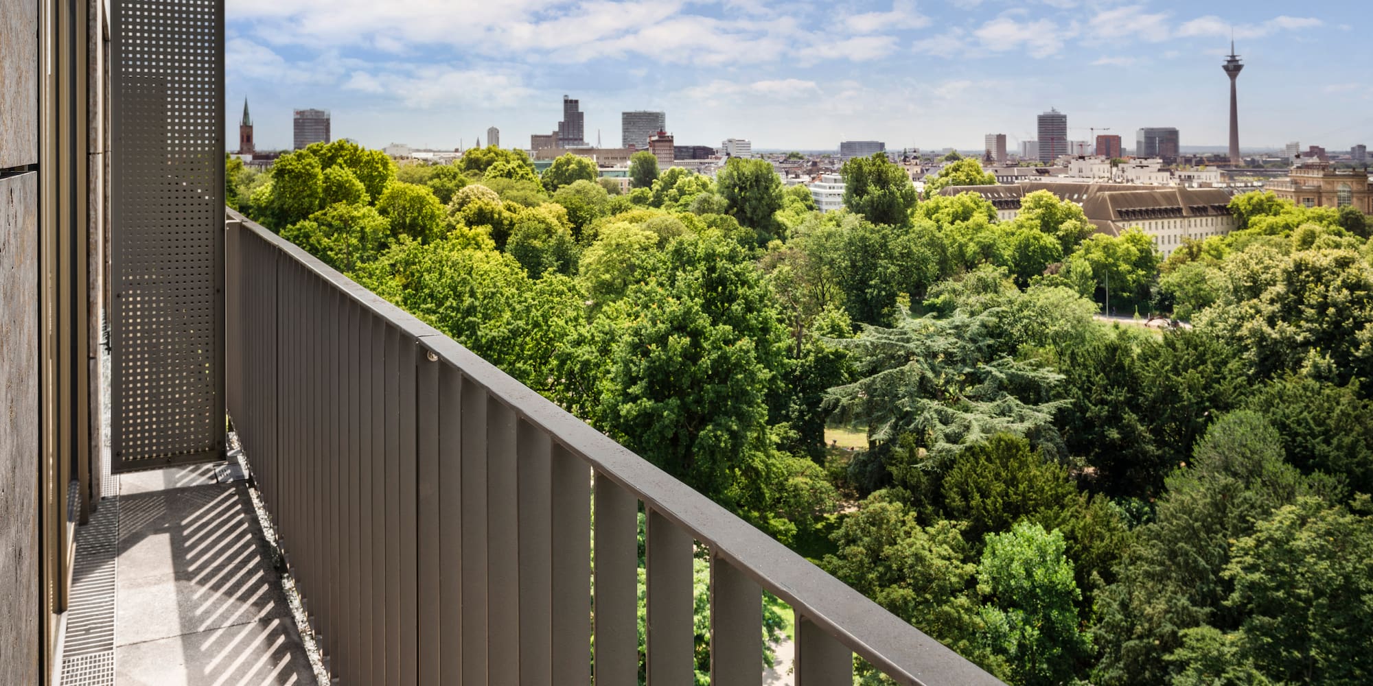 a balcony with trees and a city in the background