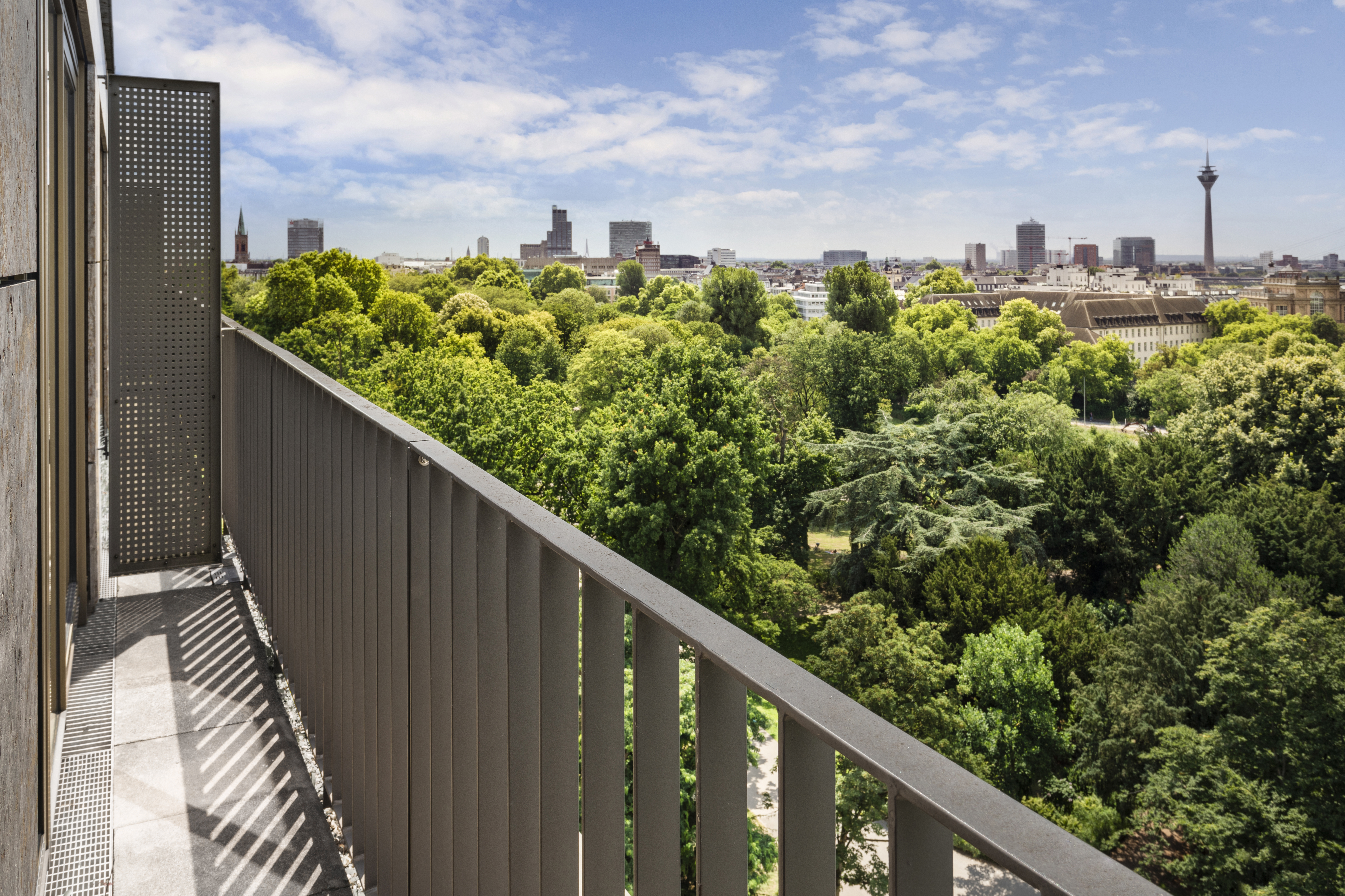 View from a balcony over a green park to the Düsseldorf city skyline.