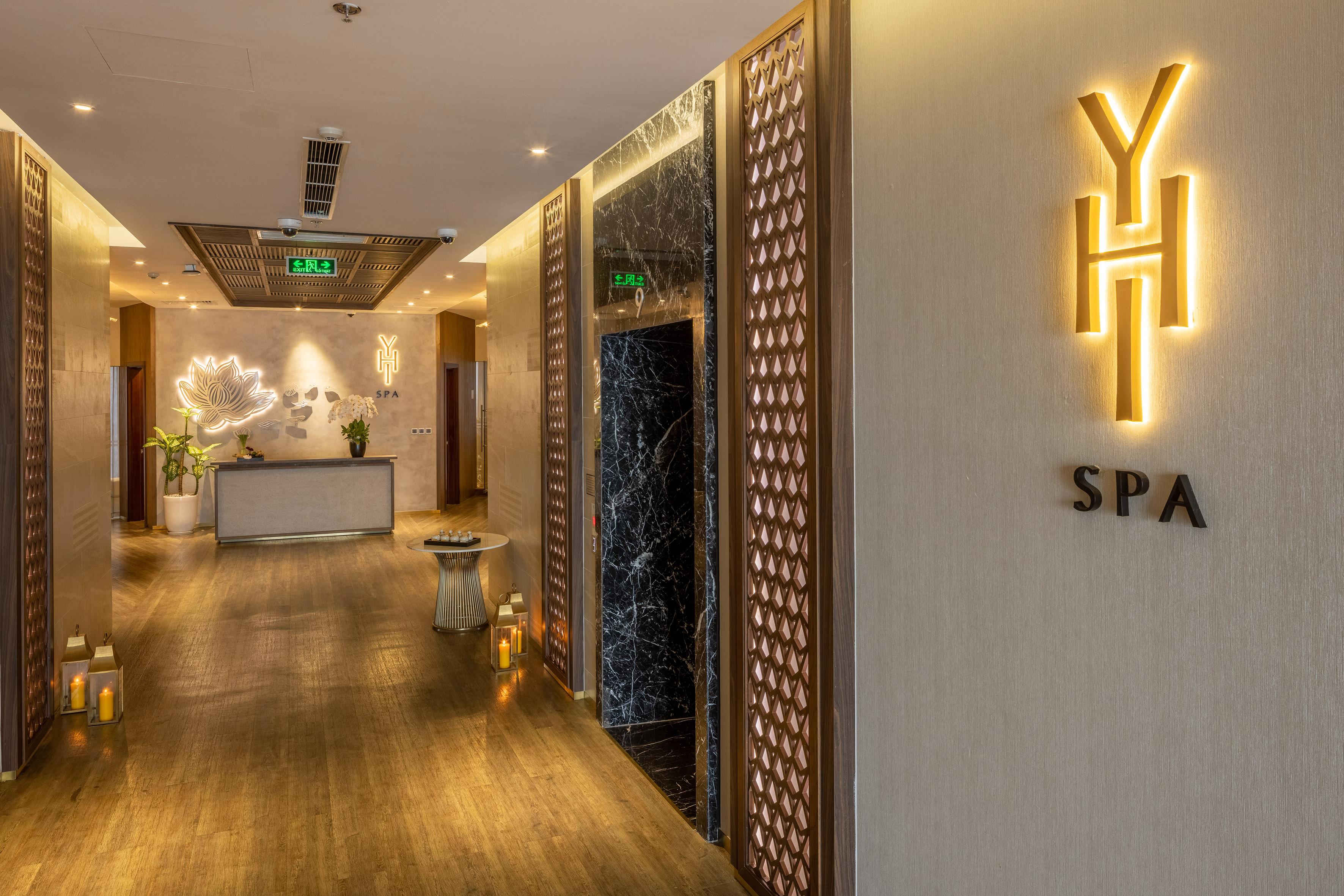 Modern spa reception with glowing lotus, wooden floor, and 'YH SPA' logo.