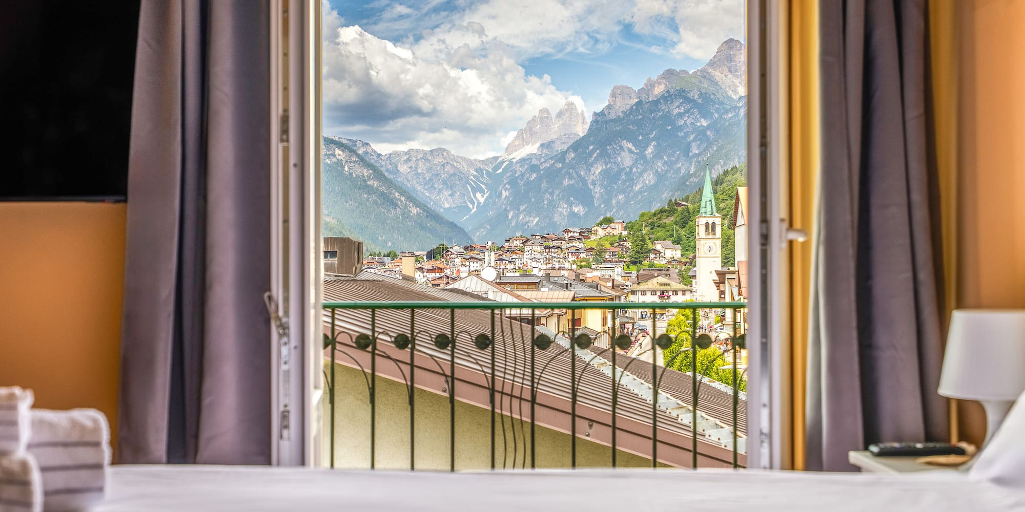 Scenic mountain village from hotel balcony, with cloudy Dolomites peaks.