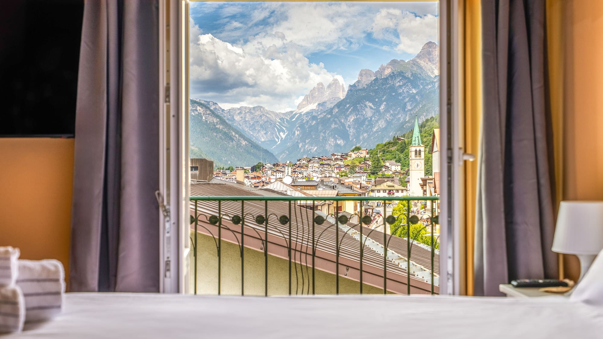 Scenic mountain village from hotel balcony, with cloudy Dolomites peaks.