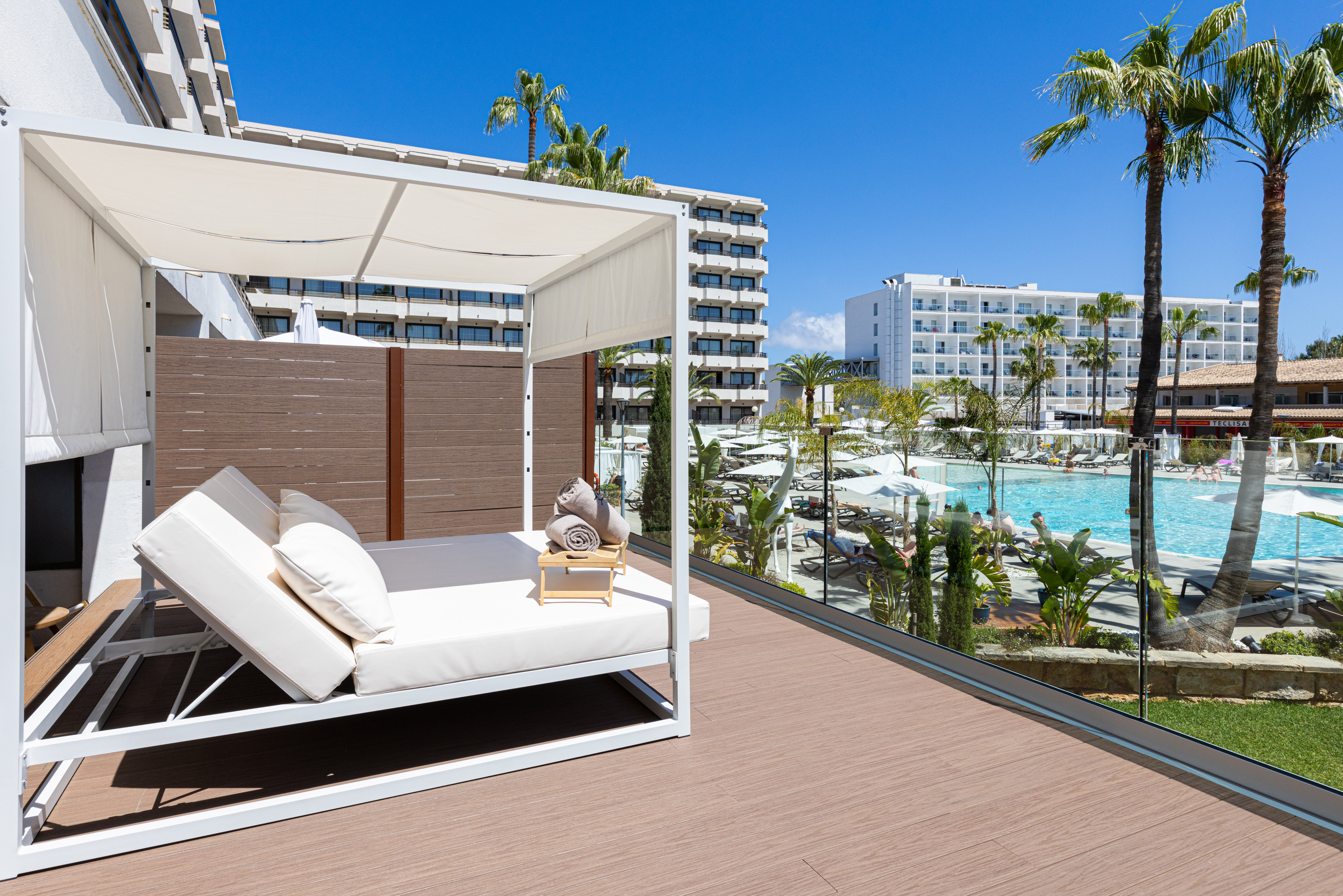 a deck with a white canopy and a pool in the background
