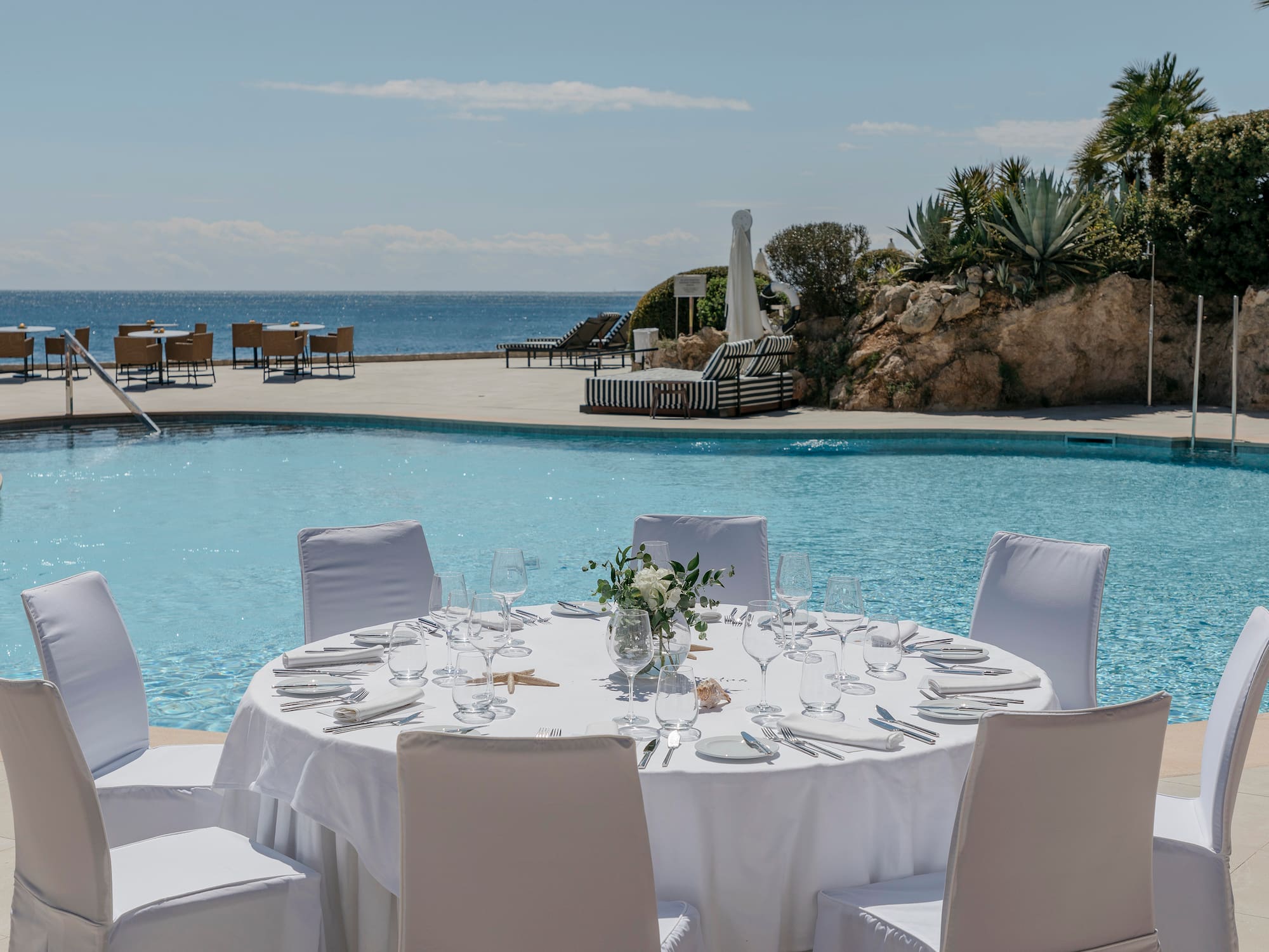 a table set for a dinner party by a pool
