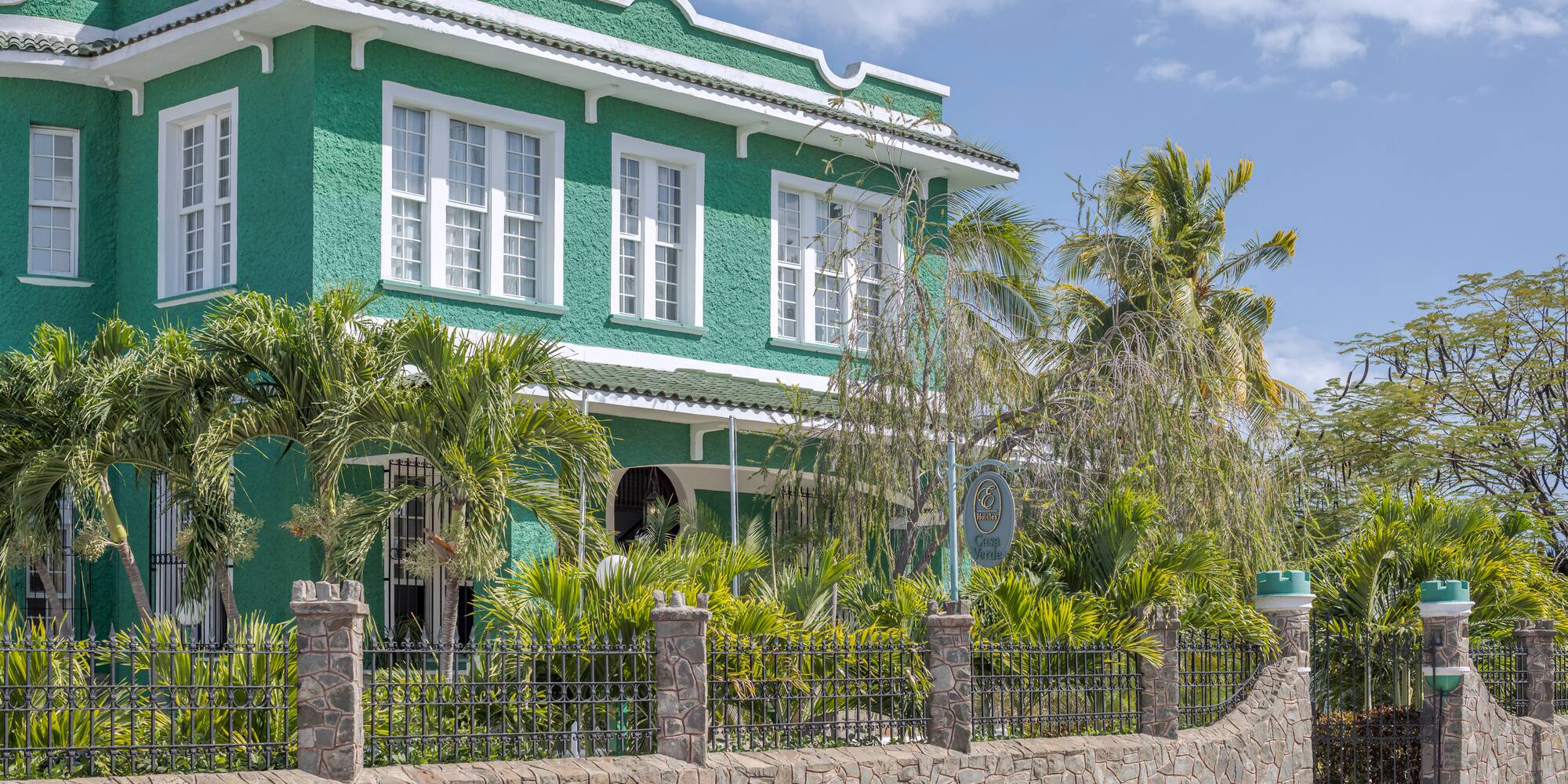 a green house with palm trees and a fence