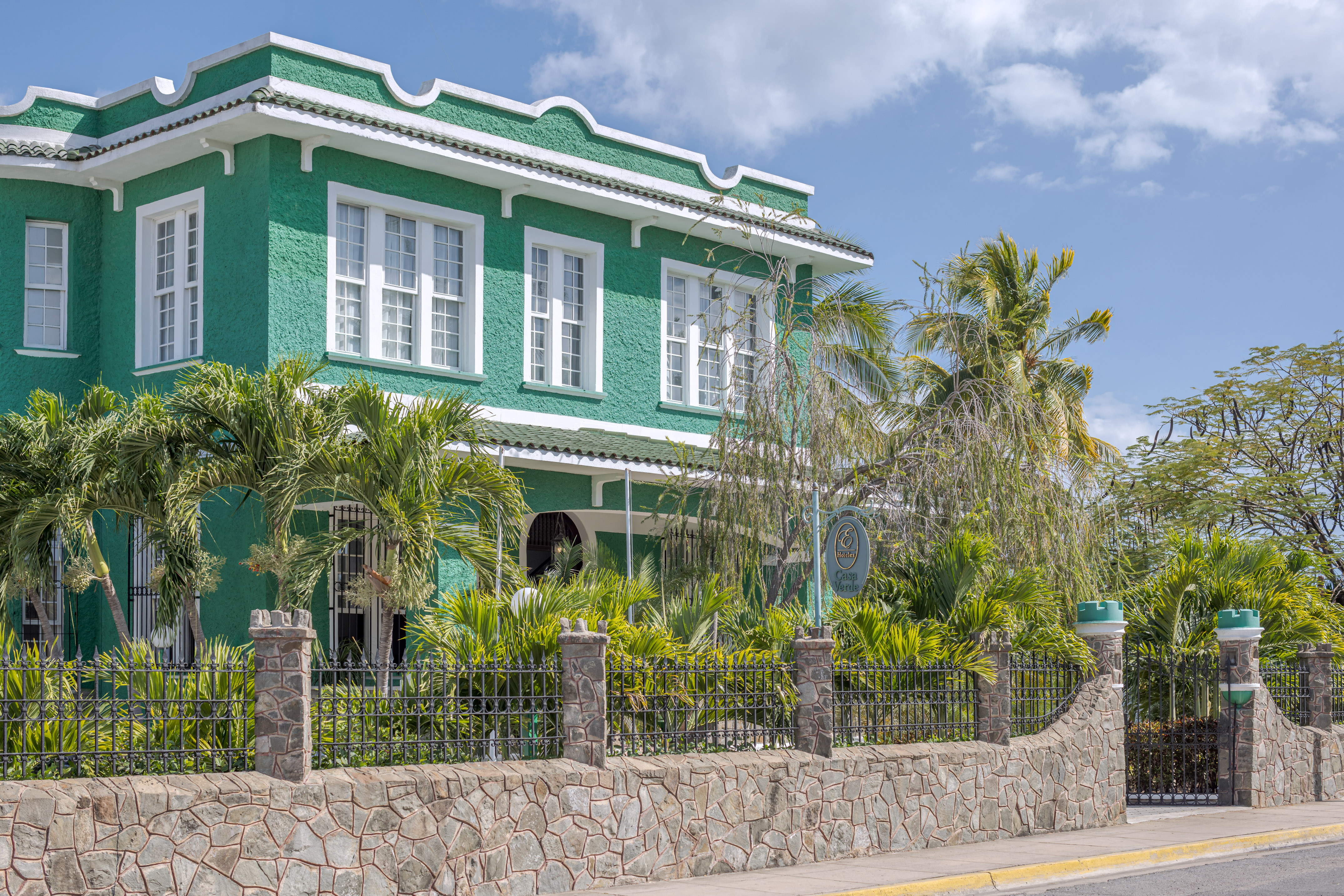 a green house with palm trees and a fence