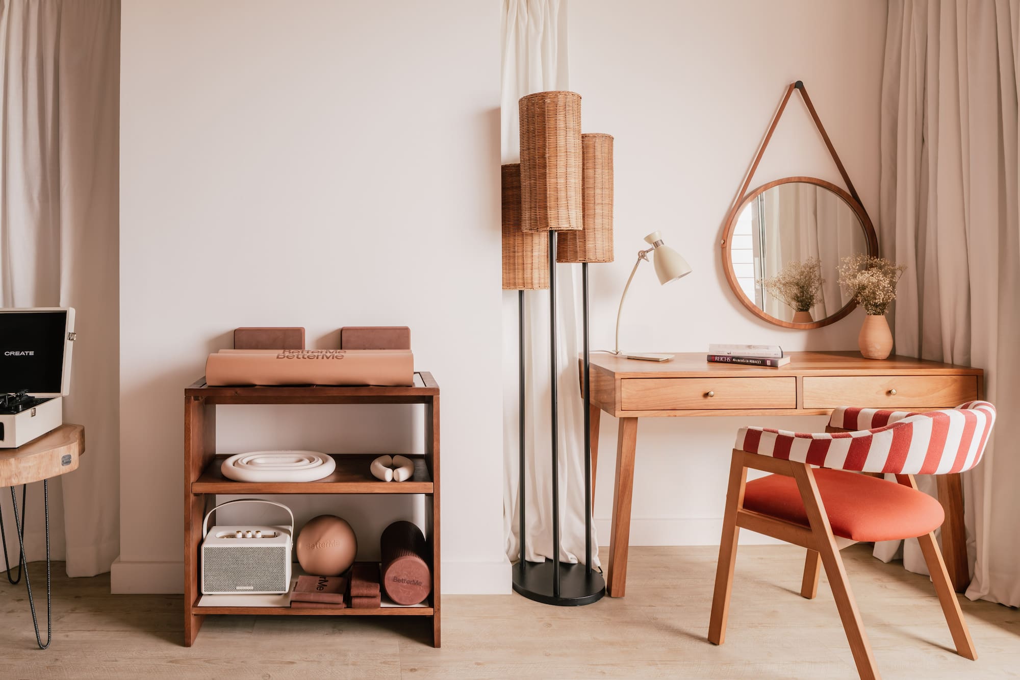 Modern interior with wooden desk, red striped chair, rattan lamp, and fitness gear.