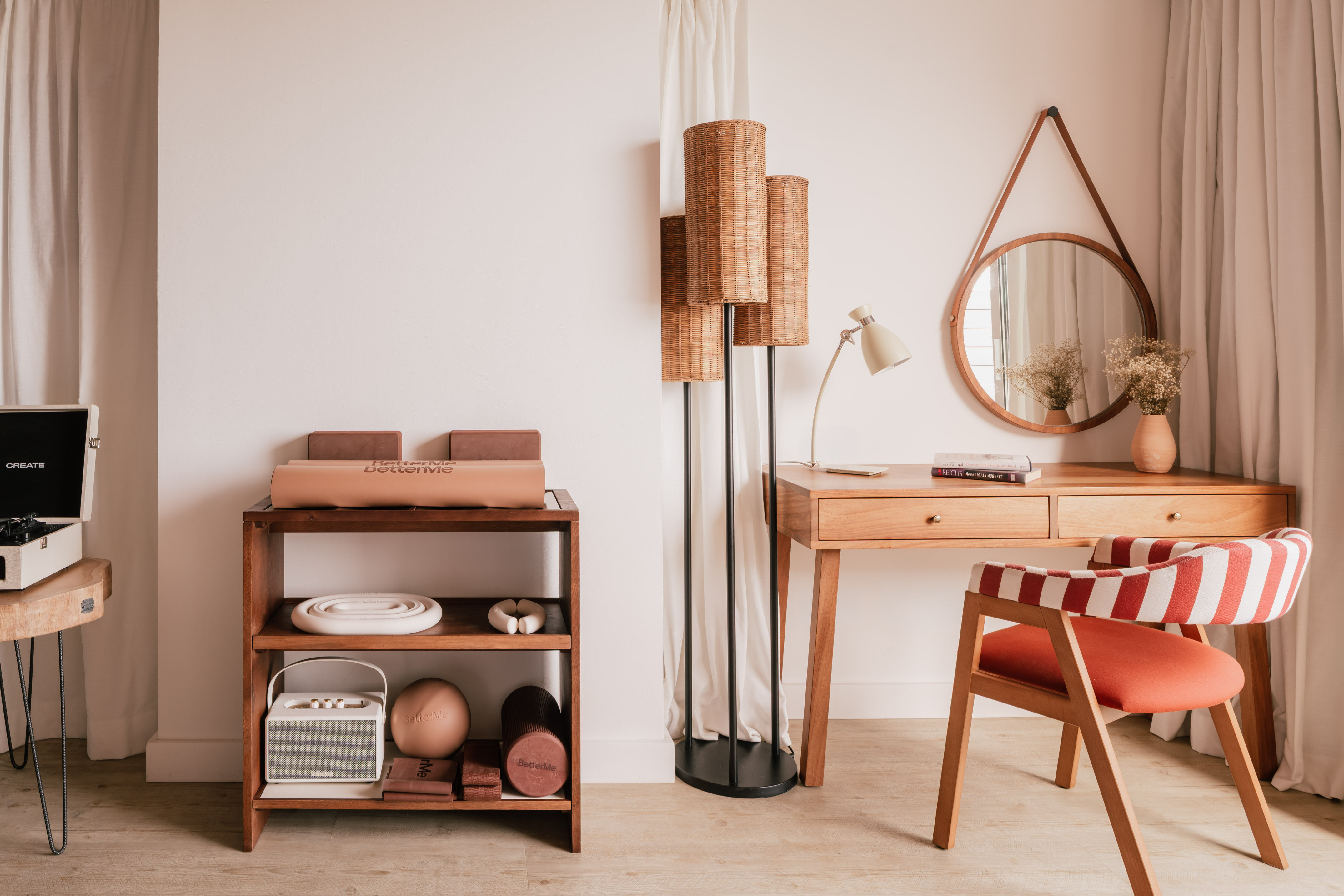 Modern interior with wooden desk, red striped chair, rattan lamp, and fitness gear.